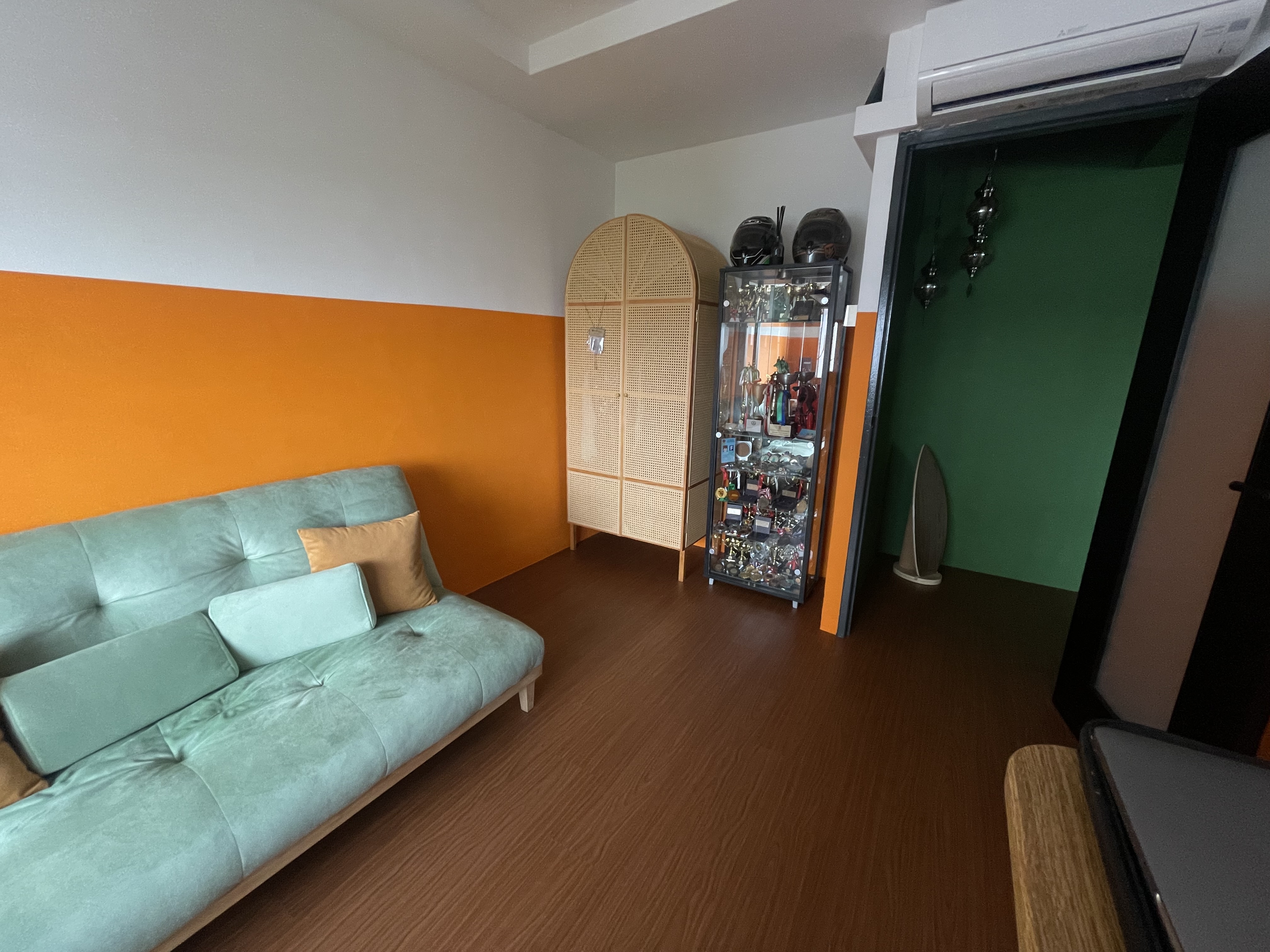 A unique blend of mid-century charm & cottage coziness - Turquoise sofa, orange and white wall, wooden floor, glass cabinet