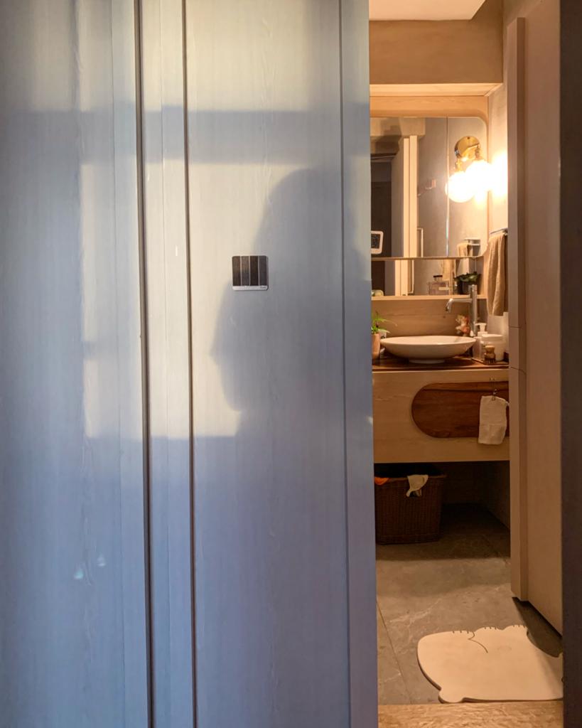 "Embracing the Magic: Day and Night Views from Our Nest ✨🌙" - Light-colored bathroom door, soft shadows, wooden vanity