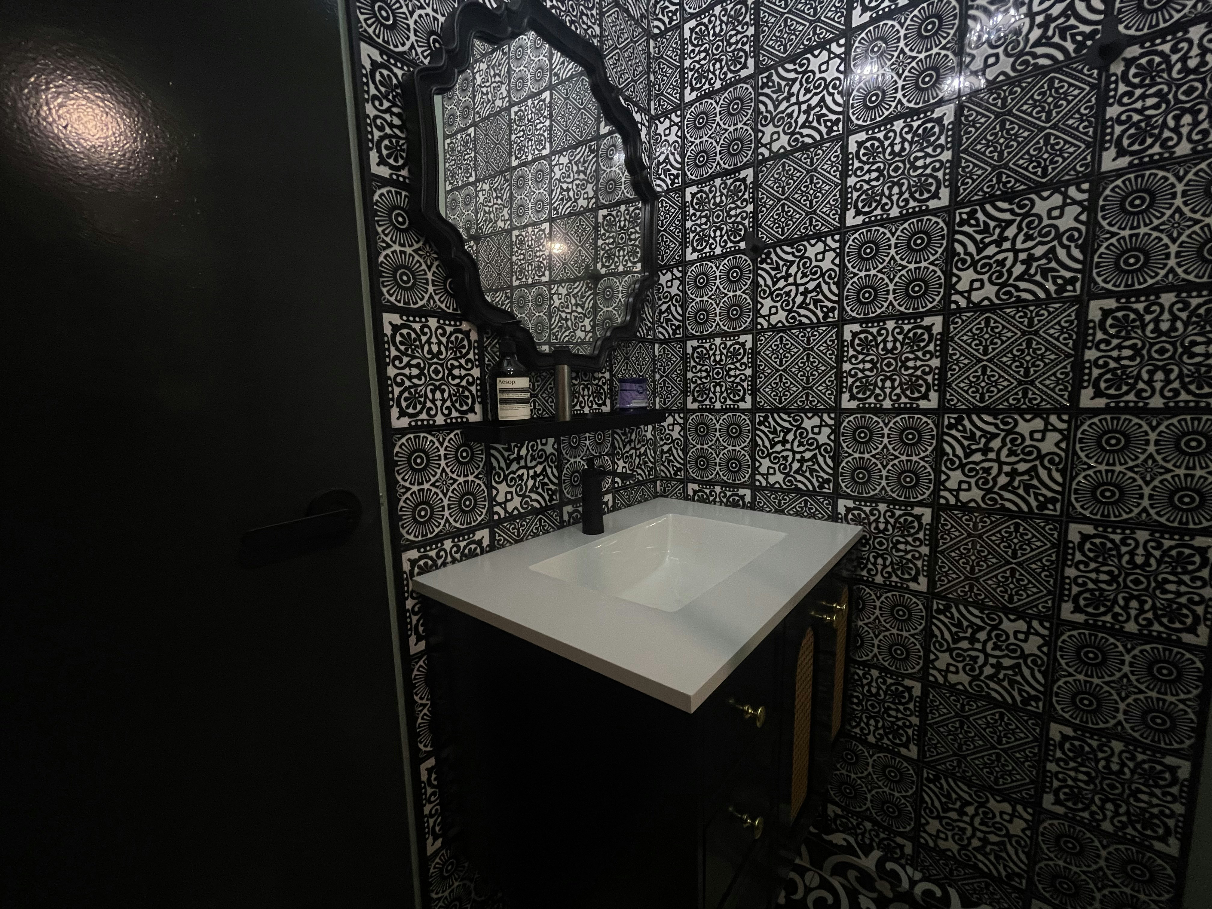A unique blend of mid-century charm & cottage coziness - Black and white patterned tiles, ornate mirror frame, sleek vanity