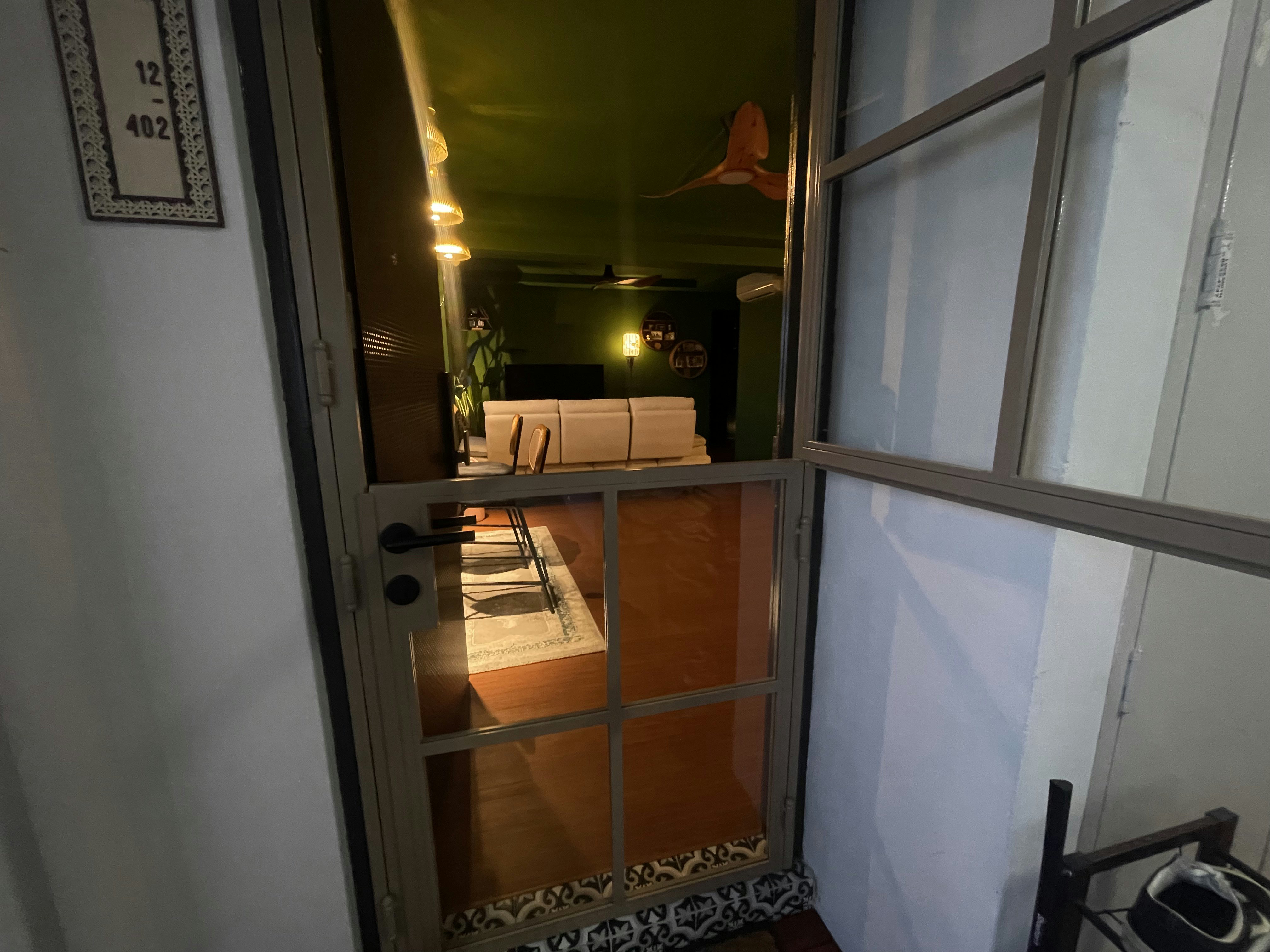 A unique blend of mid-century charm & cottage coziness - Interior view of a cozy living room with a green wall and modern