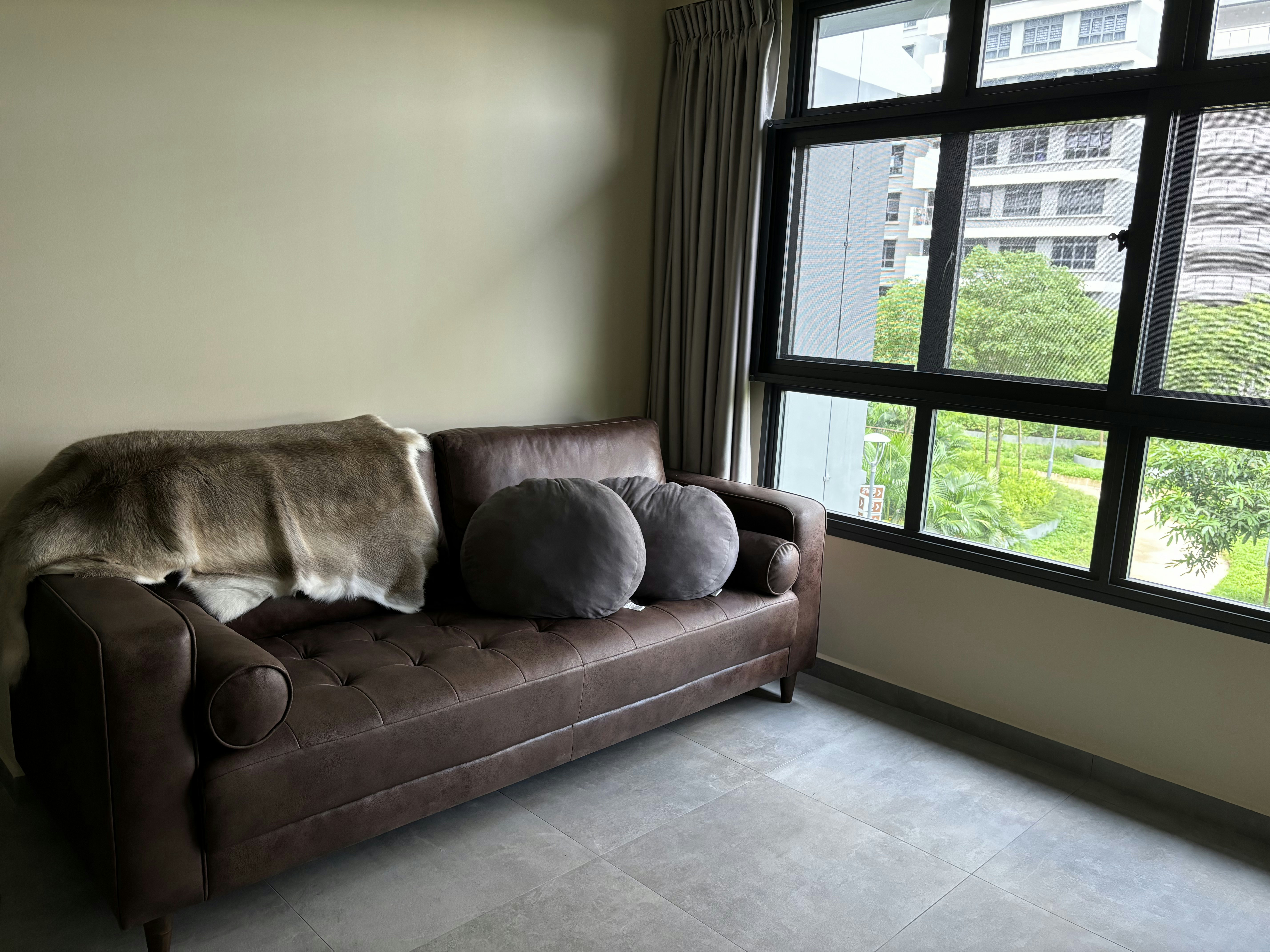 Inside a practical Modern Mediterranean 4RM BTO - Brown leather sofa, gray cushions, beige fur throw, large window, gray