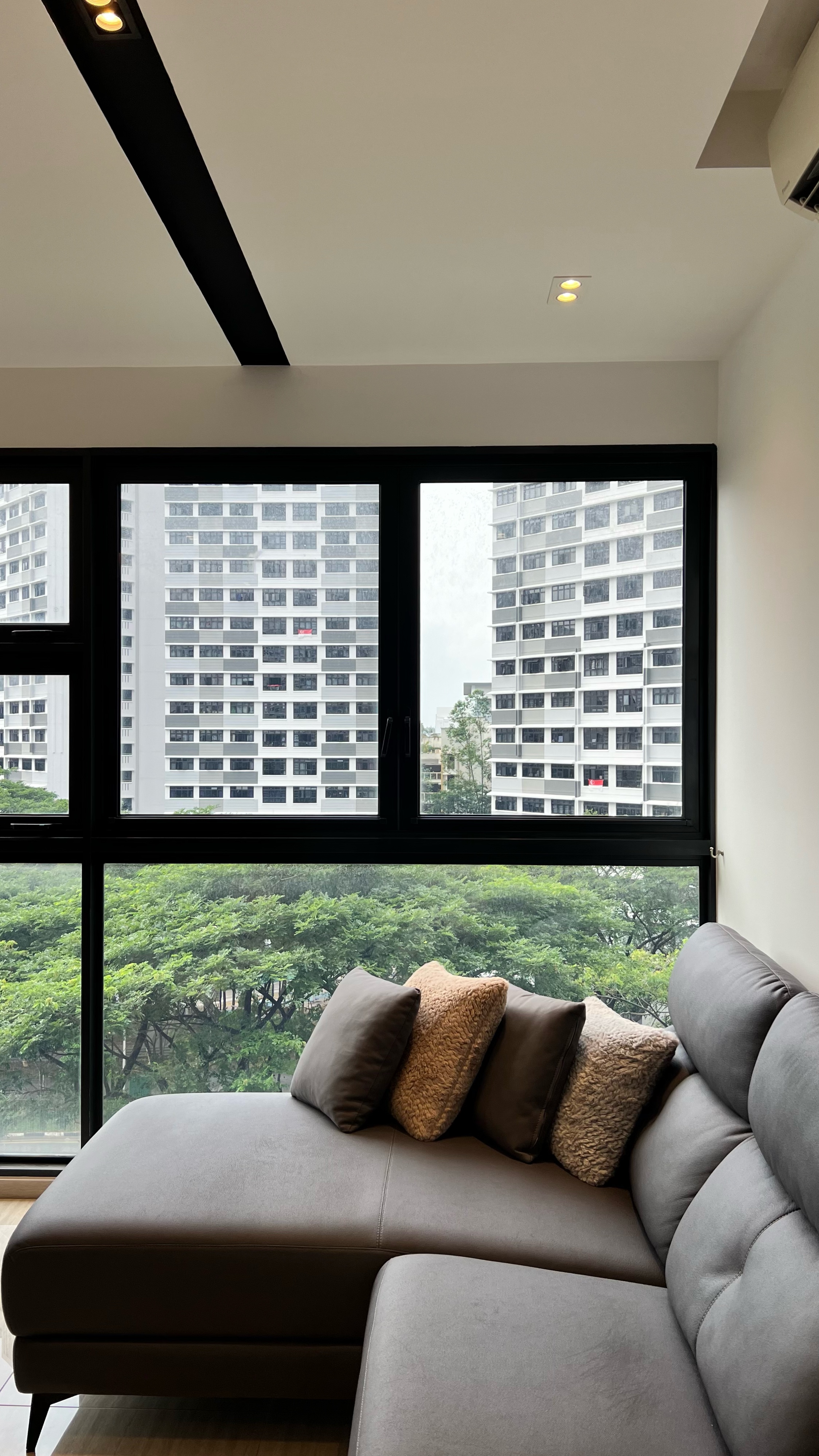 Our little cosmopolitan treehouse! - Large modern living room with gray sectional sofa, large floor-to-ceiling windows, city