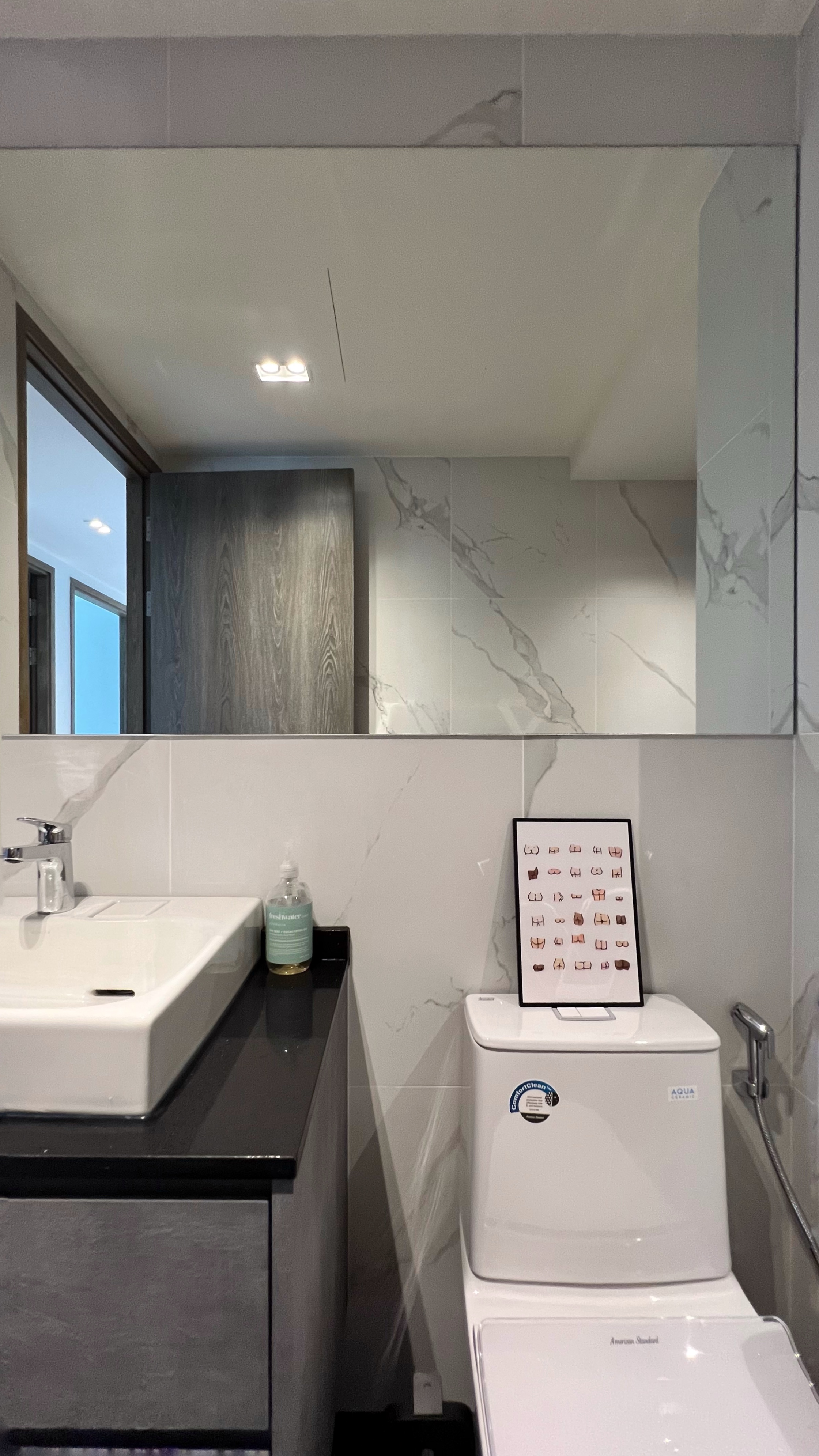 Our little cosmopolitan treehouse! - White sink with modern faucet, sleek bathroom vanity, black countertop, mirror above