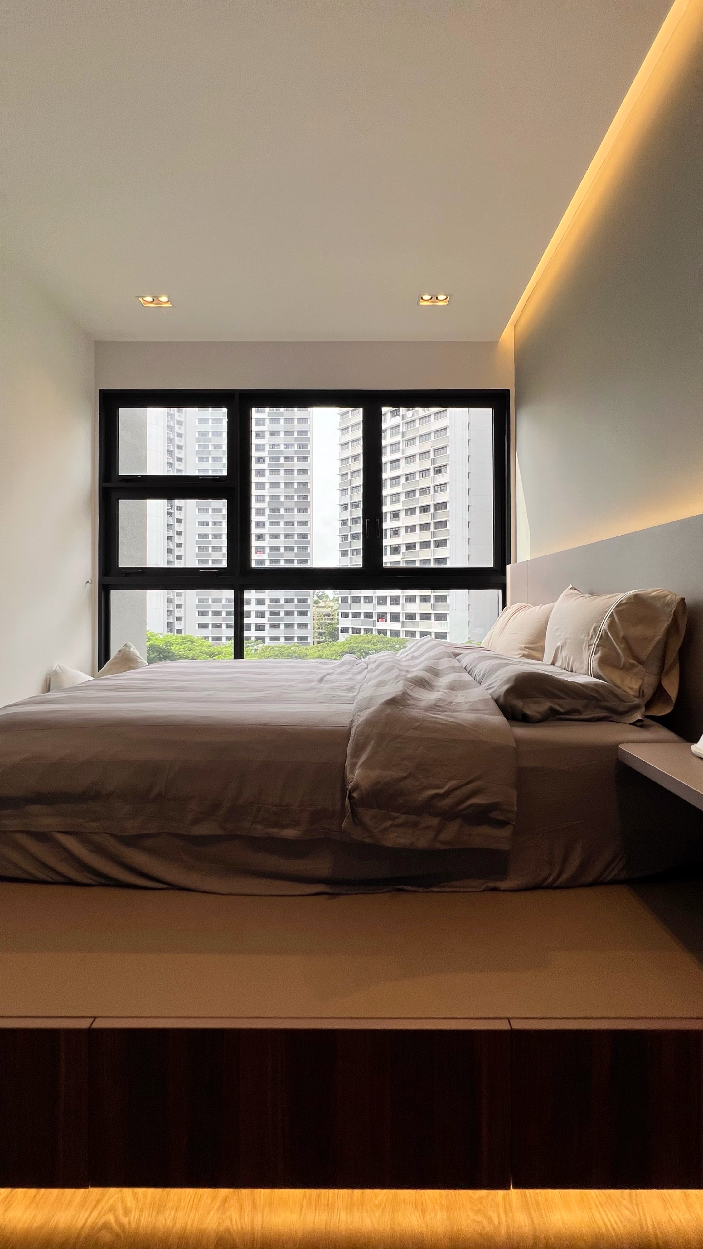 Our little cosmopolitan treehouse! - Modern bedroom with large window, neutral color palette, neatly made bed, soft lighting