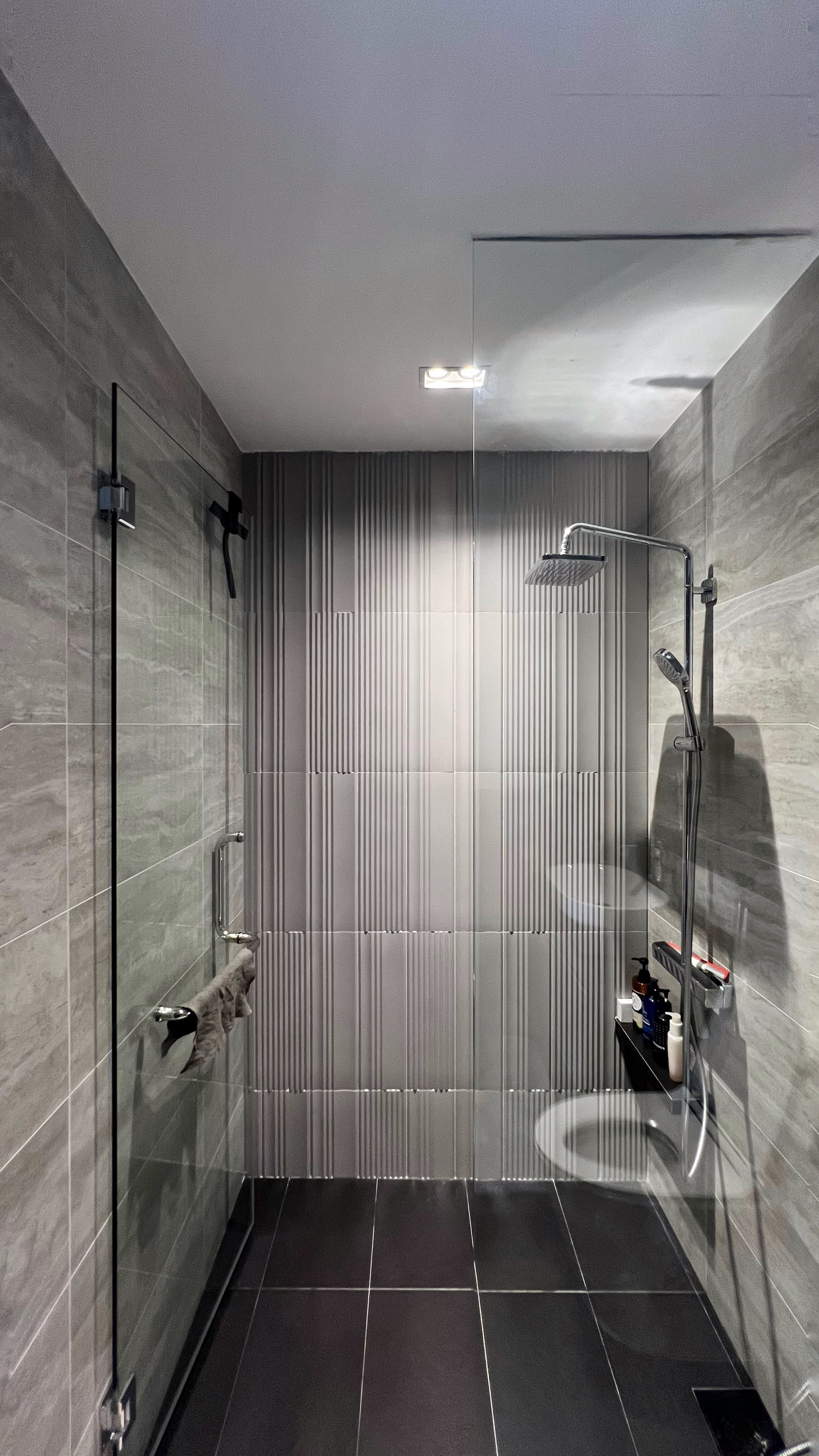 Our little cosmopolitan treehouse! - Grey tiled walls, modern shower, sleek fixtures, glass shower enclosure, black tiles