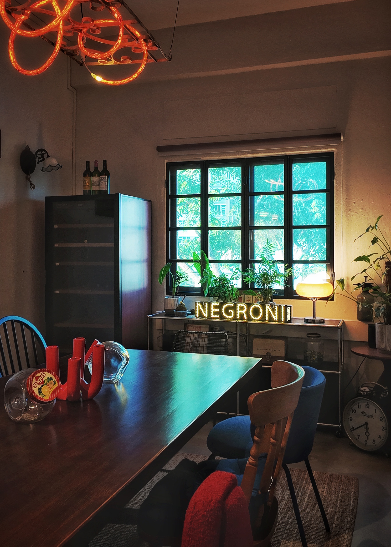 A moody vintage walk-up apartment in Lavender - Modern dining room, cozy ambiance, warm lighting, large window, green plants