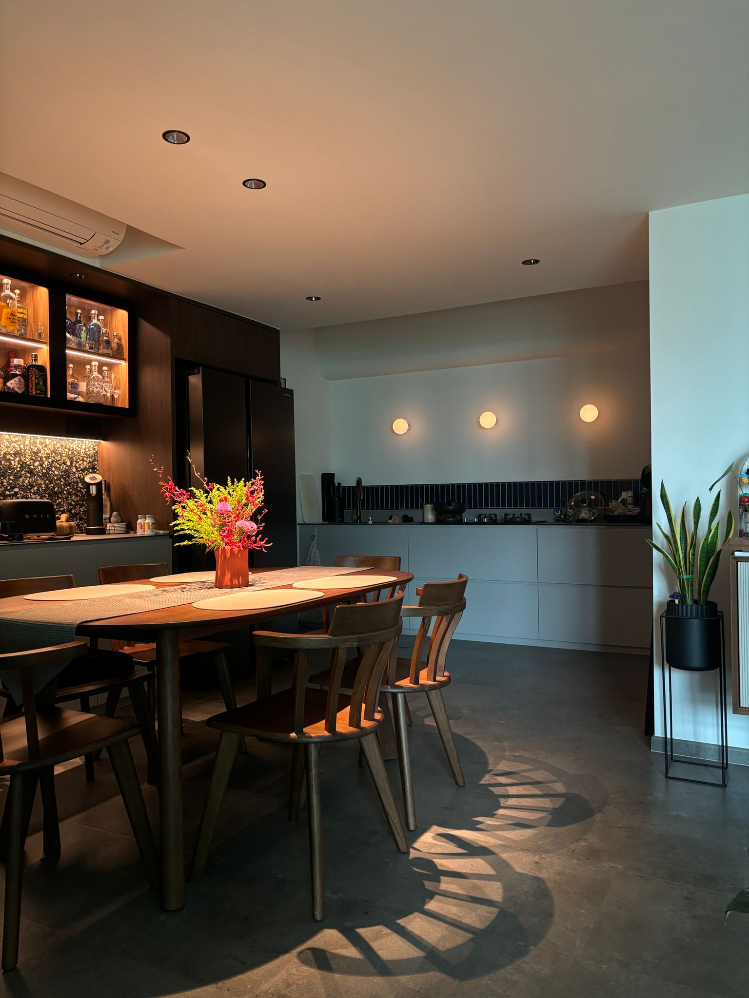 Envisioning your space - Renders vs Reality - Modern kitchen with wooden dining table, sleek dark cabinetry, vibrant flower