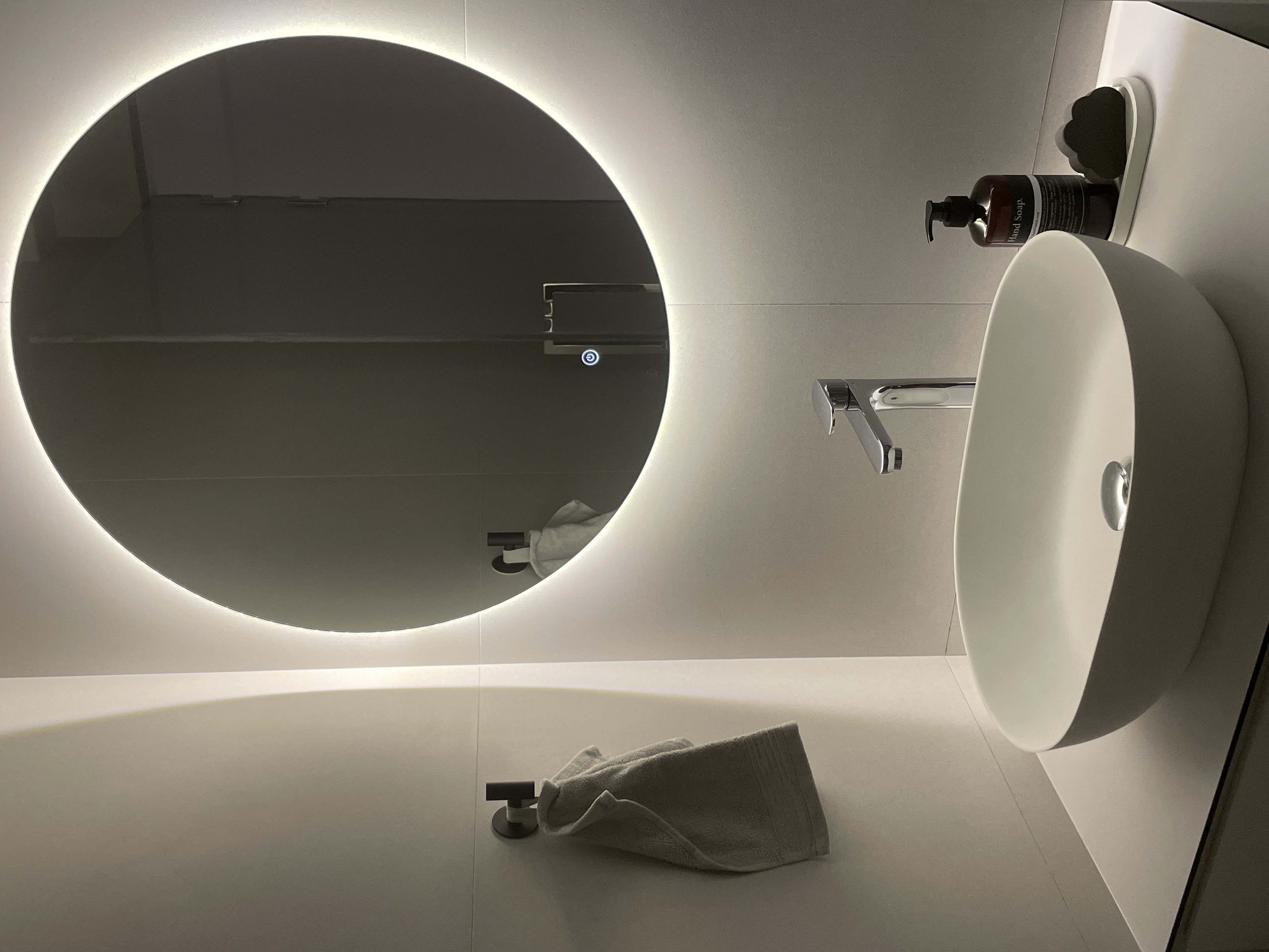 A Peek Inside Our Minimalist Sanctuary  - Modern minimalist bathroom, sleek design, circular mirror, ambient lighting