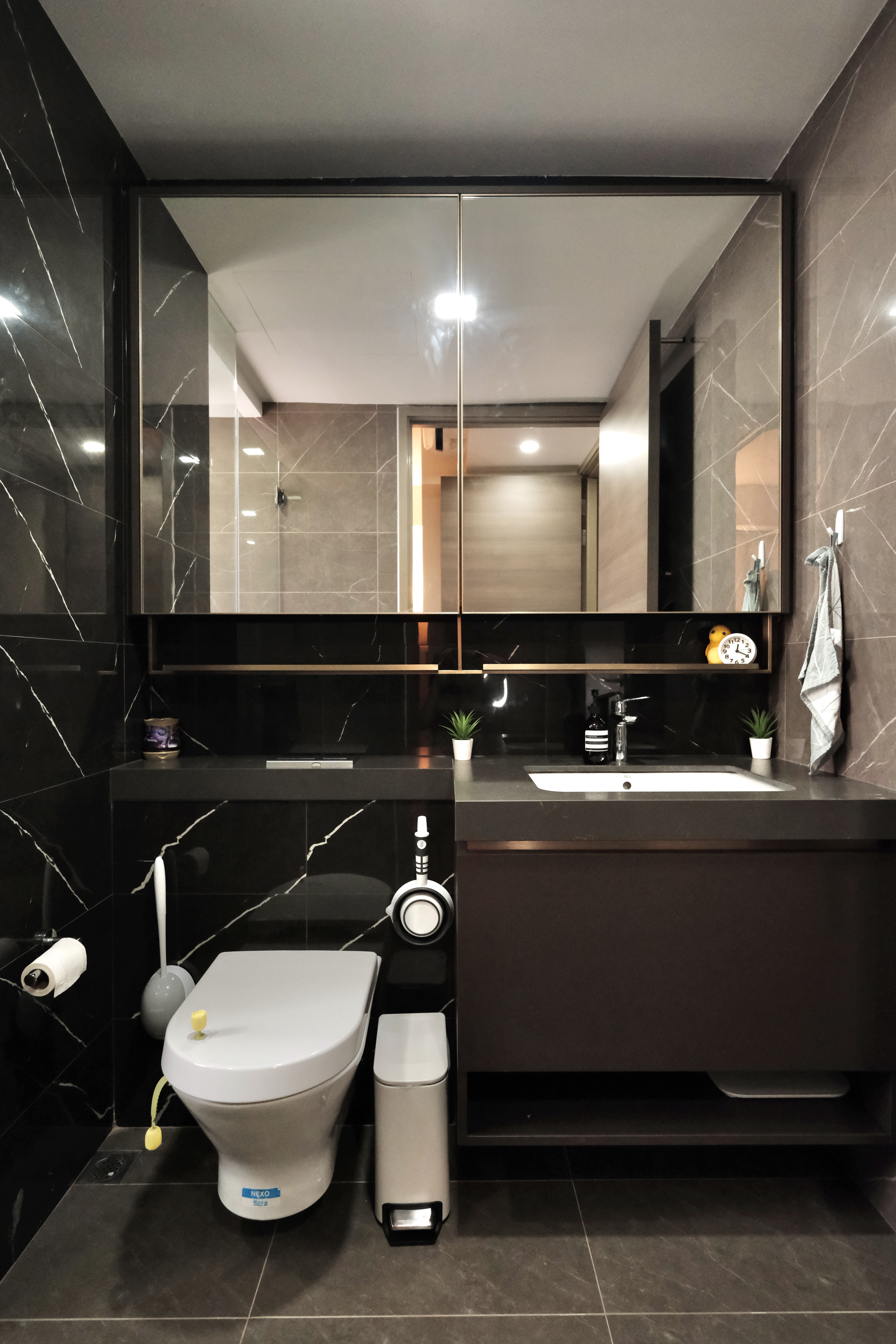 Minimalist Cozy Living in the North-East - Modern bathroom with sleek black and gray marble tiles, large mirror, contemporary
