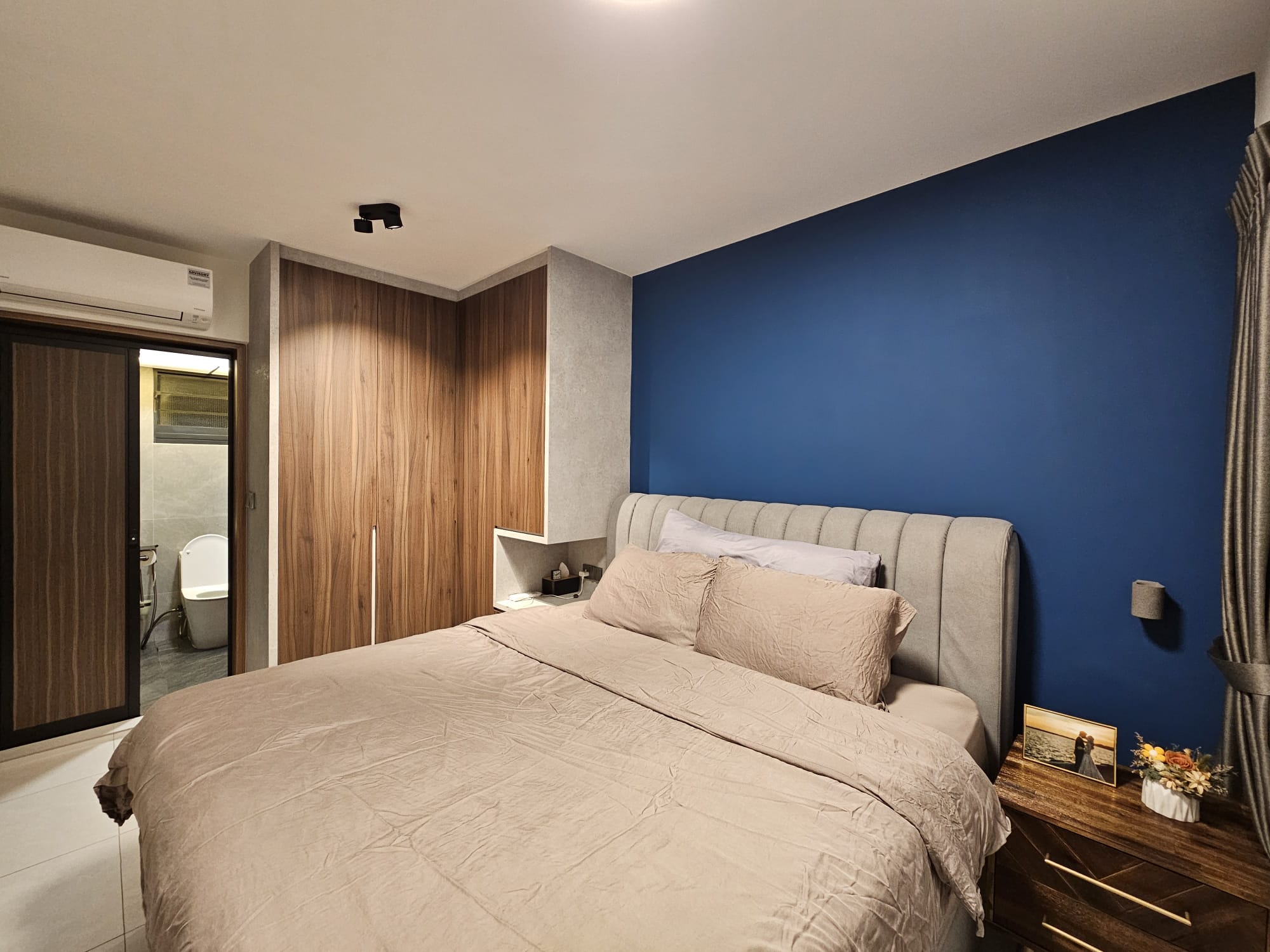 House Tour: Exploring Dark Wood Mid-Century Modern Theme - Modern bedroom with beige bedding, wooden wardrobe, blue accent