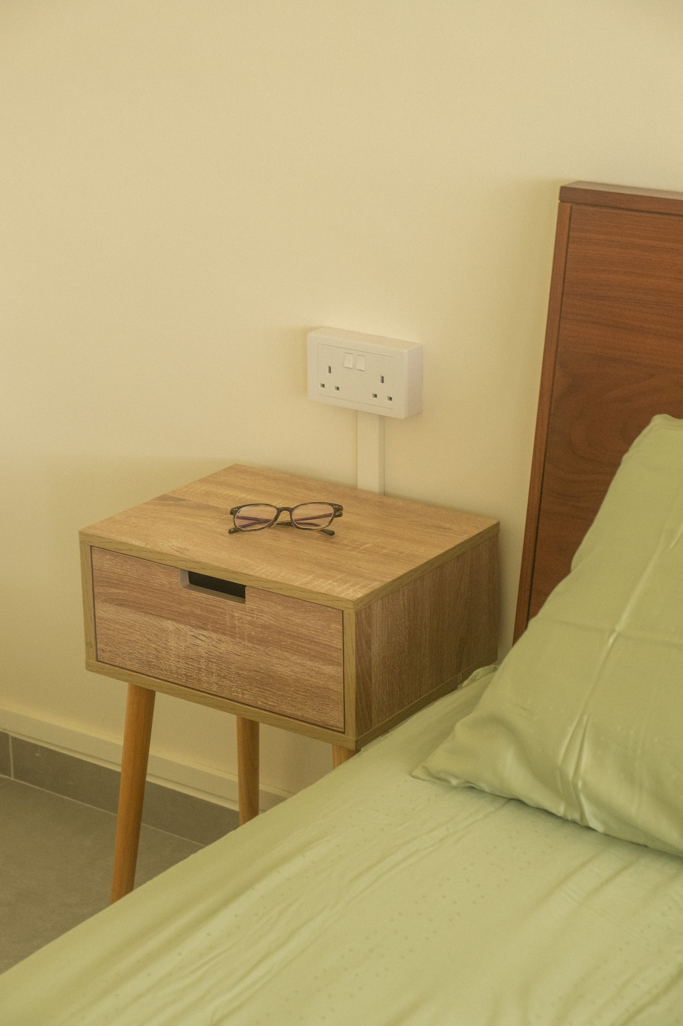 Maximising space in our cosy & quirky home with cats - Wooden nightstand with glasses, light green bedspread, beige wall