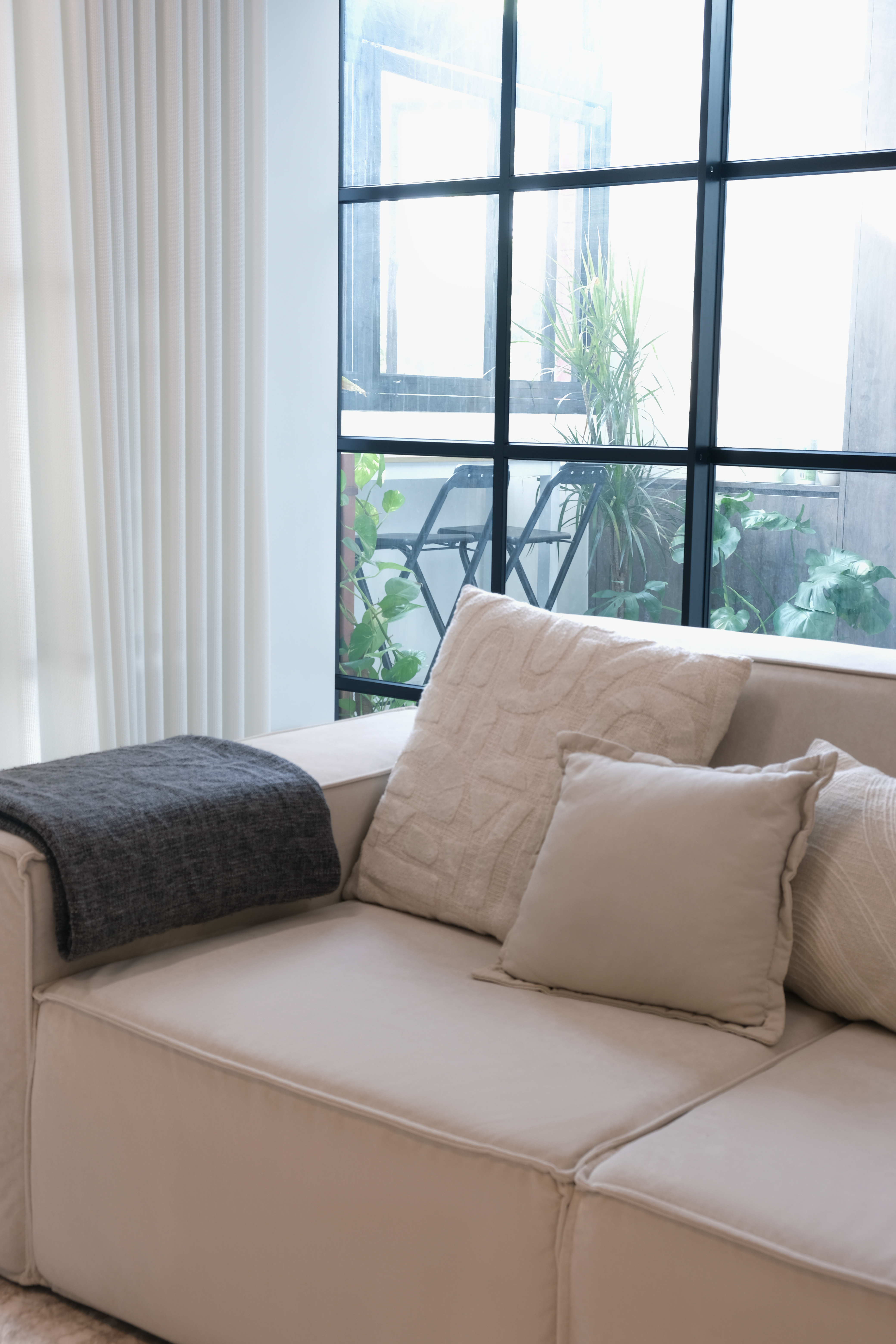 Inside a 300k Reno Modern Gallery-Inspired Maisonette - Cream-colored sofa, beige and gray pillows, large window with black