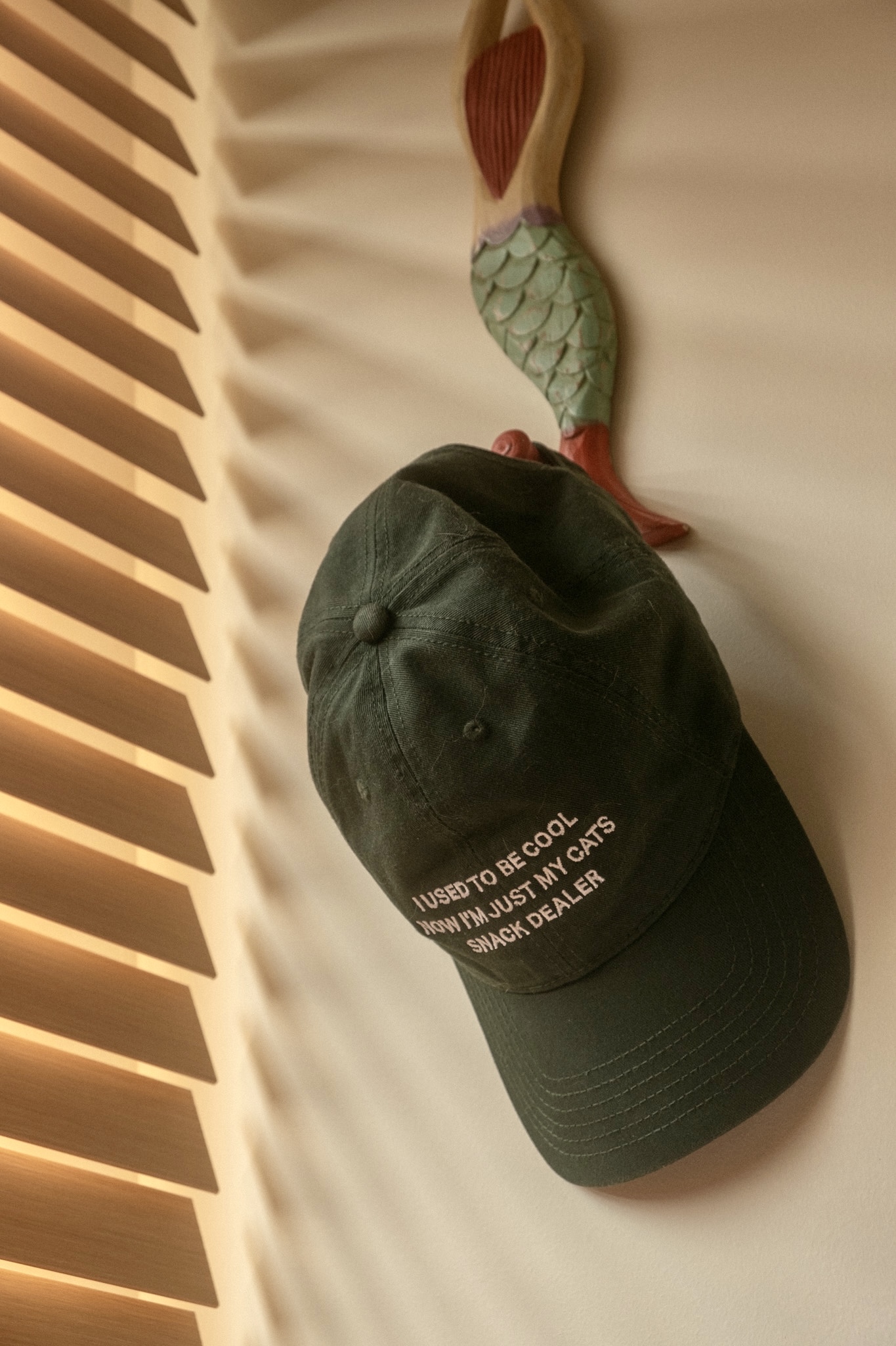 Maximising space in our cosy & quirky home with cats - Green baseball cap with text on front, Wall-mounted fish decoration