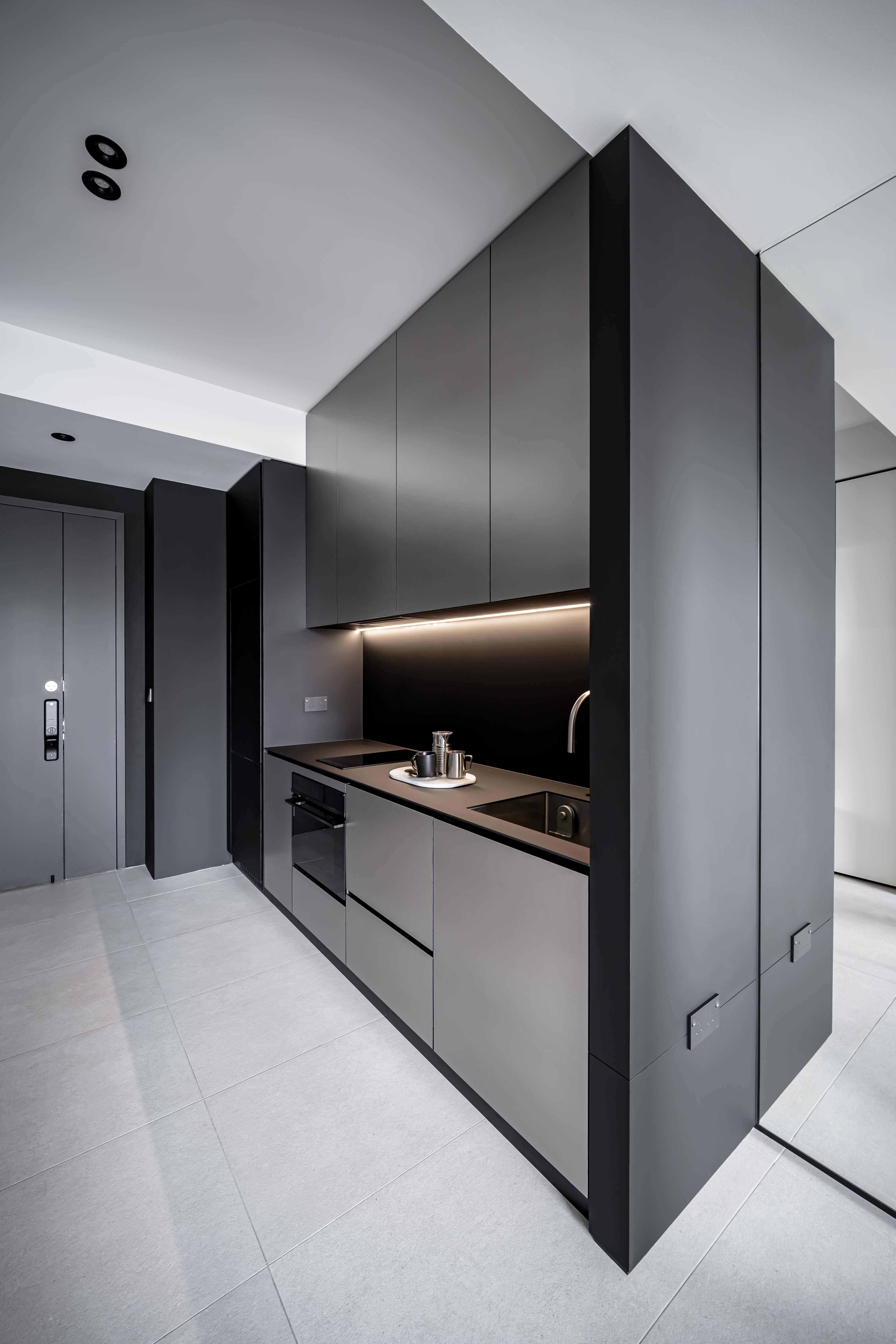 A Chic Modern Apartment Filled with Colors and Objects - Modern kitchen with sleek, dark gray cabinetry, minimalist design