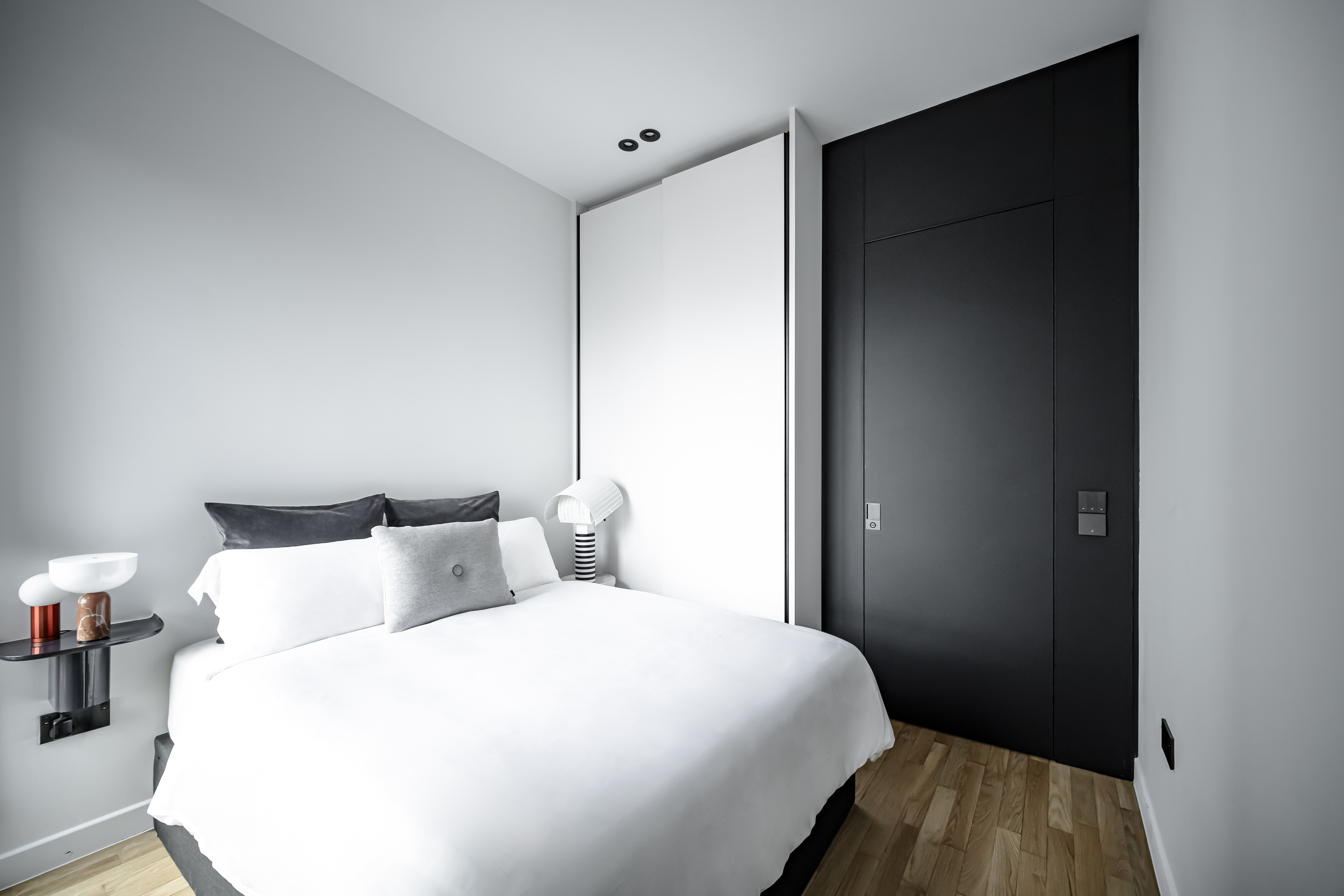 A Chic Modern Apartment Filled with Colors and Objects - Modern minimalist bedroom, sleek black wardrobe, white bed with gray
