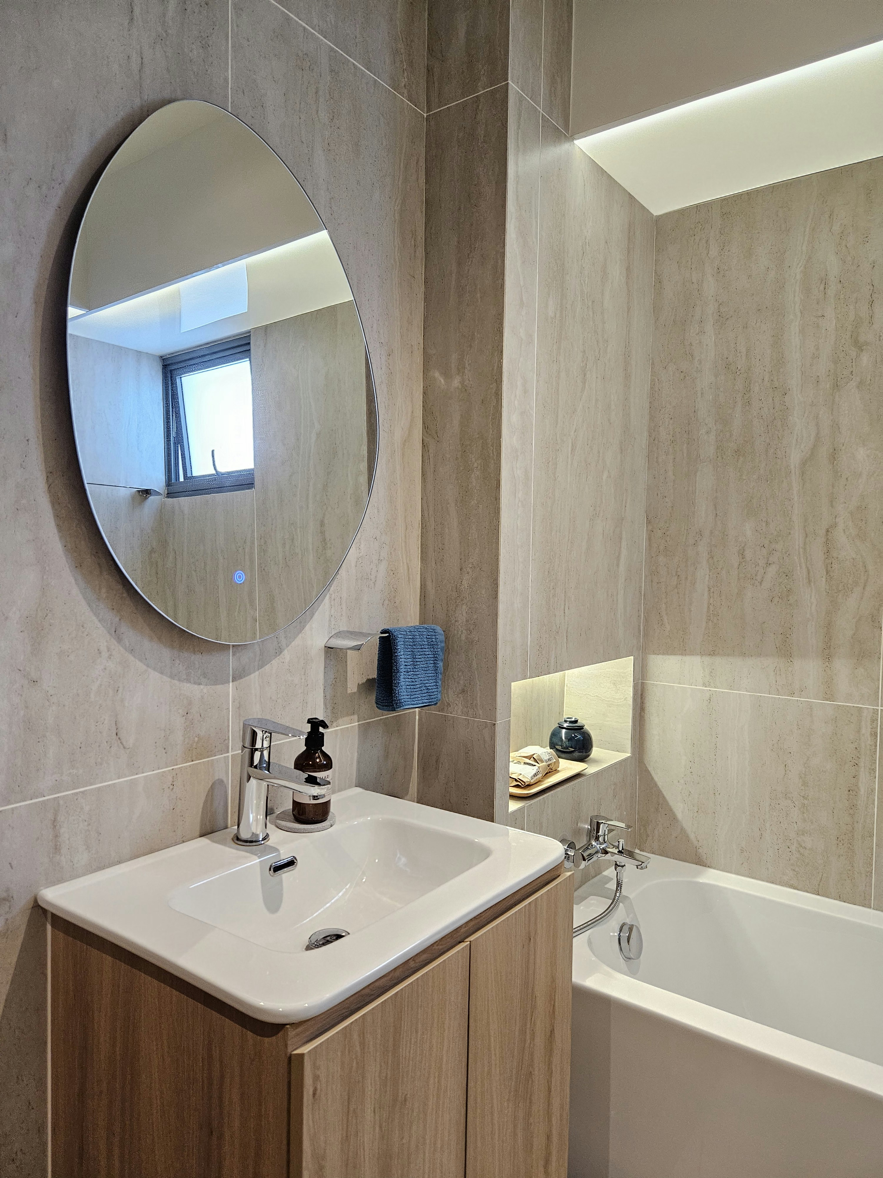 Step into our wood and pottery-filled 5-Room BTO - Round mirror, bathroom vanity, white sink, wooden cabinet, blue towel