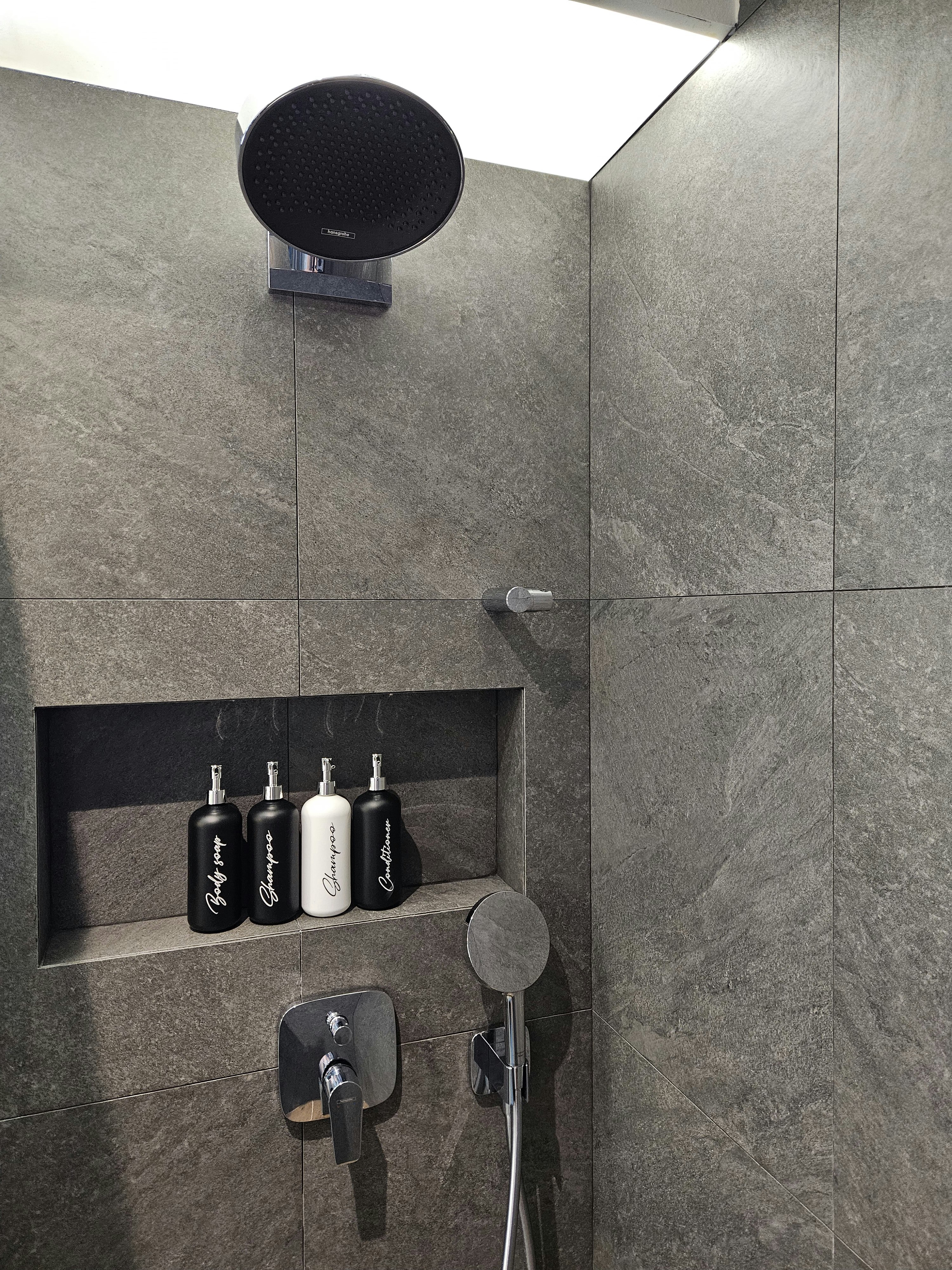 Step into our wood and pottery-filled 5-Room BTO - Grey marble tiles, modern showerhead, black and white bottles, black soap