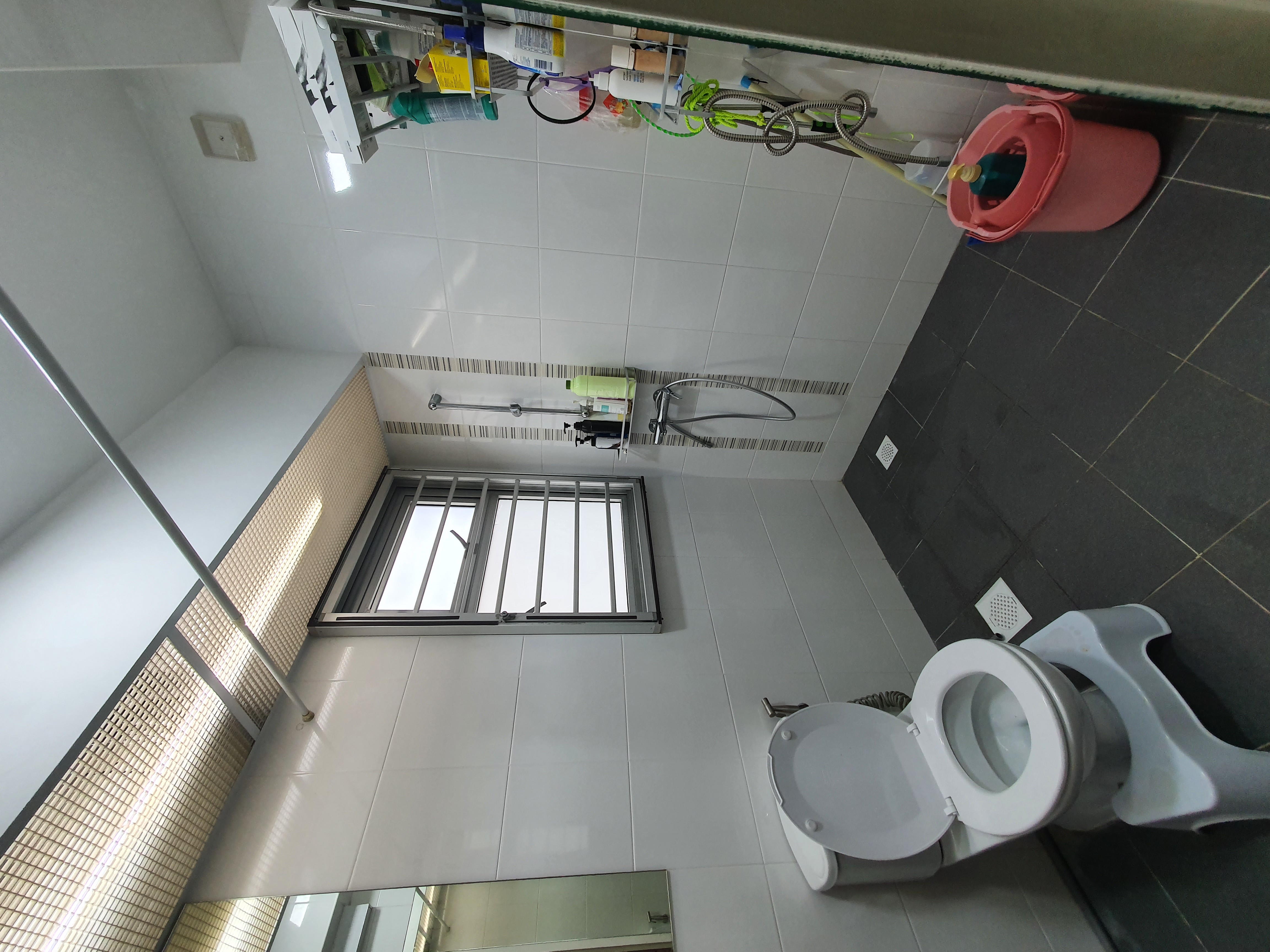 4-Room Warm, Minimalist Smart HDB Reno (50k) - White tiled walls, gray floor, window with bars, metal railing, pink bucket