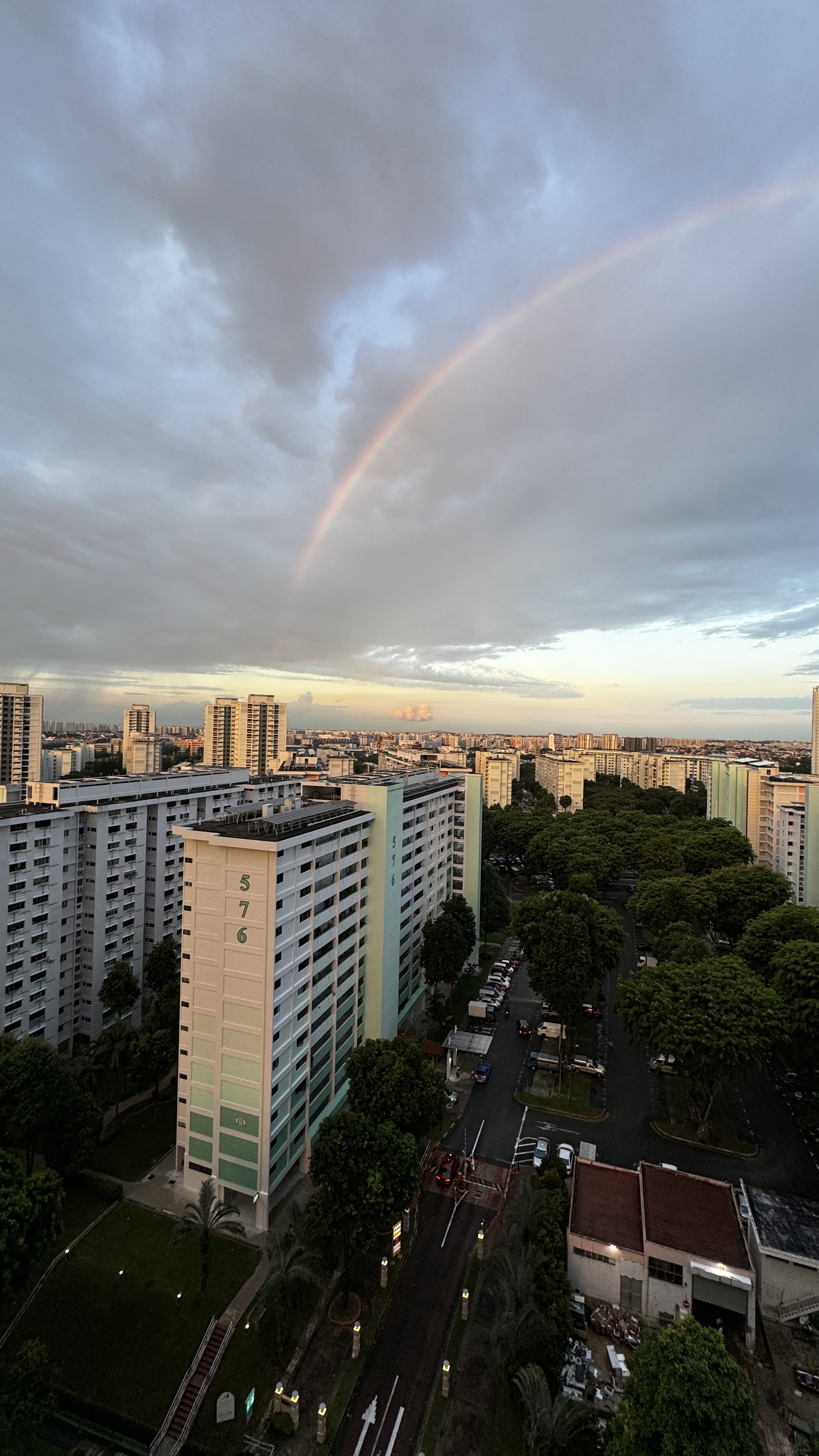 🏠 The Journey to Finding The Little Starry Loft - Rainbow arches across a cityscape at dusk, casting a warm glow over urban