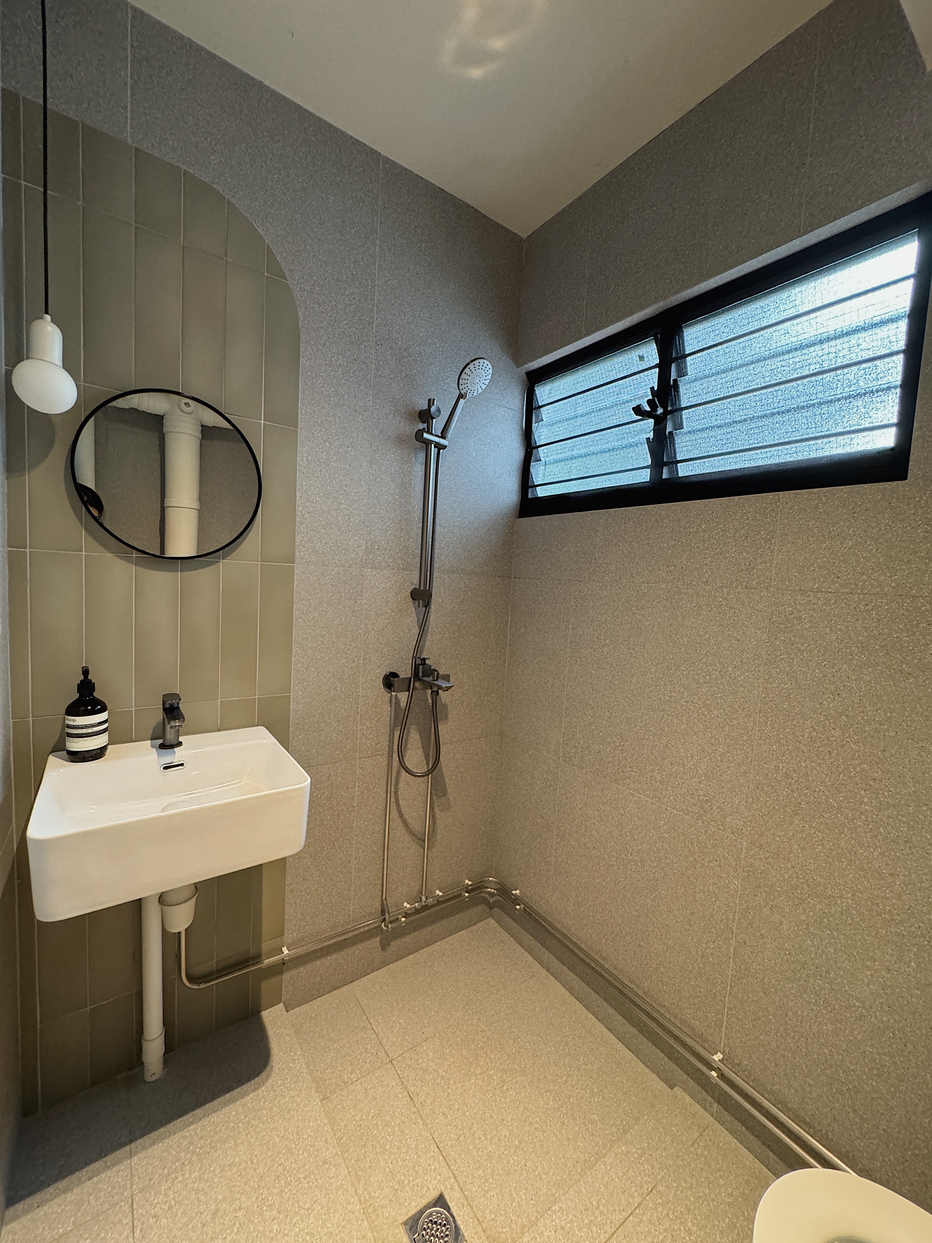 Tips & Tricks for Renovation Rendering - Modern bathroom with gray tiles, white sink, black faucet, round mirror, showerhead