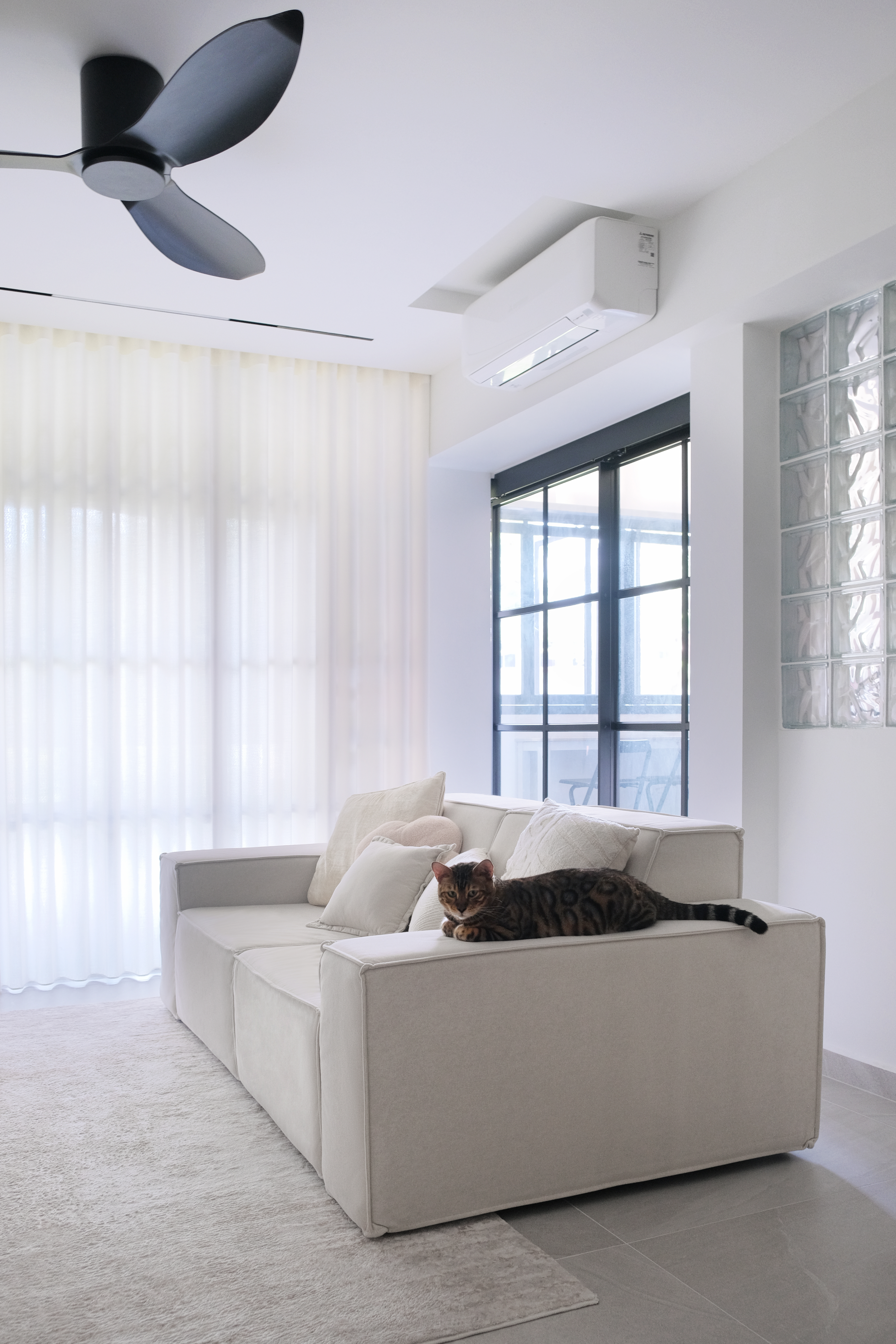 Inside a 300k Reno Modern Gallery-Inspired Maisonette - White modern living room with beige sofa, cat lounging on sofa, large