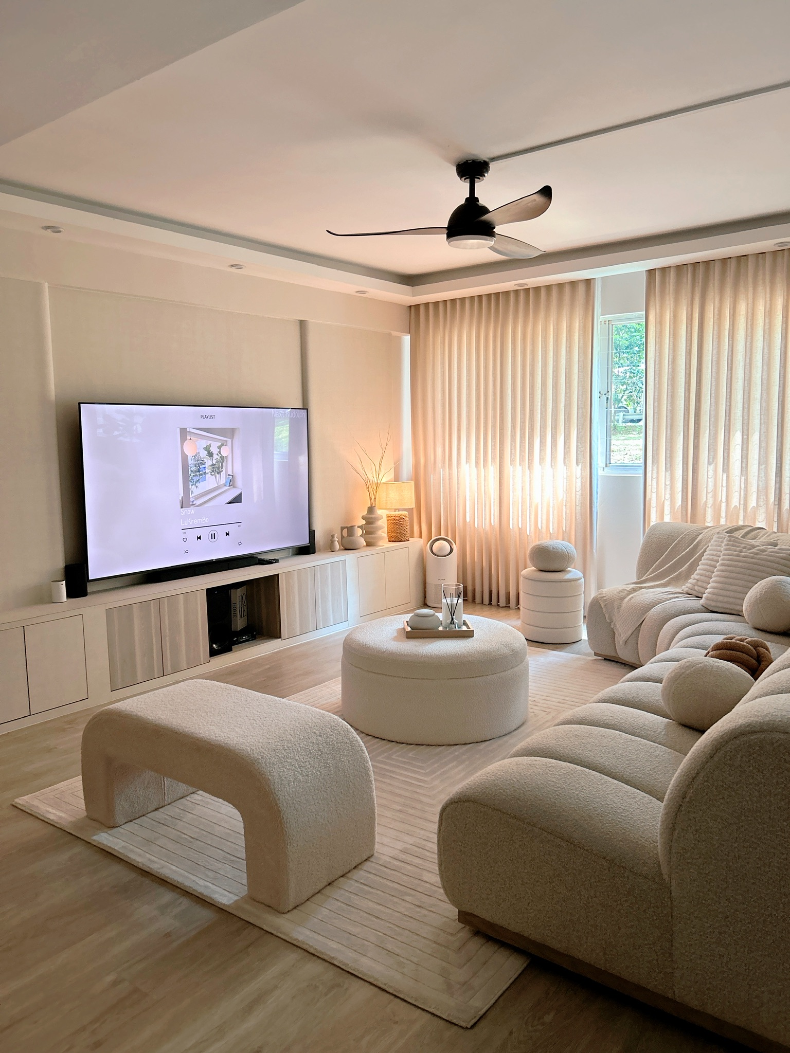 Creating Comfort: Our Personalized Home Decor - Modern living room with large flat-screen TV, beige plush sofa, circular