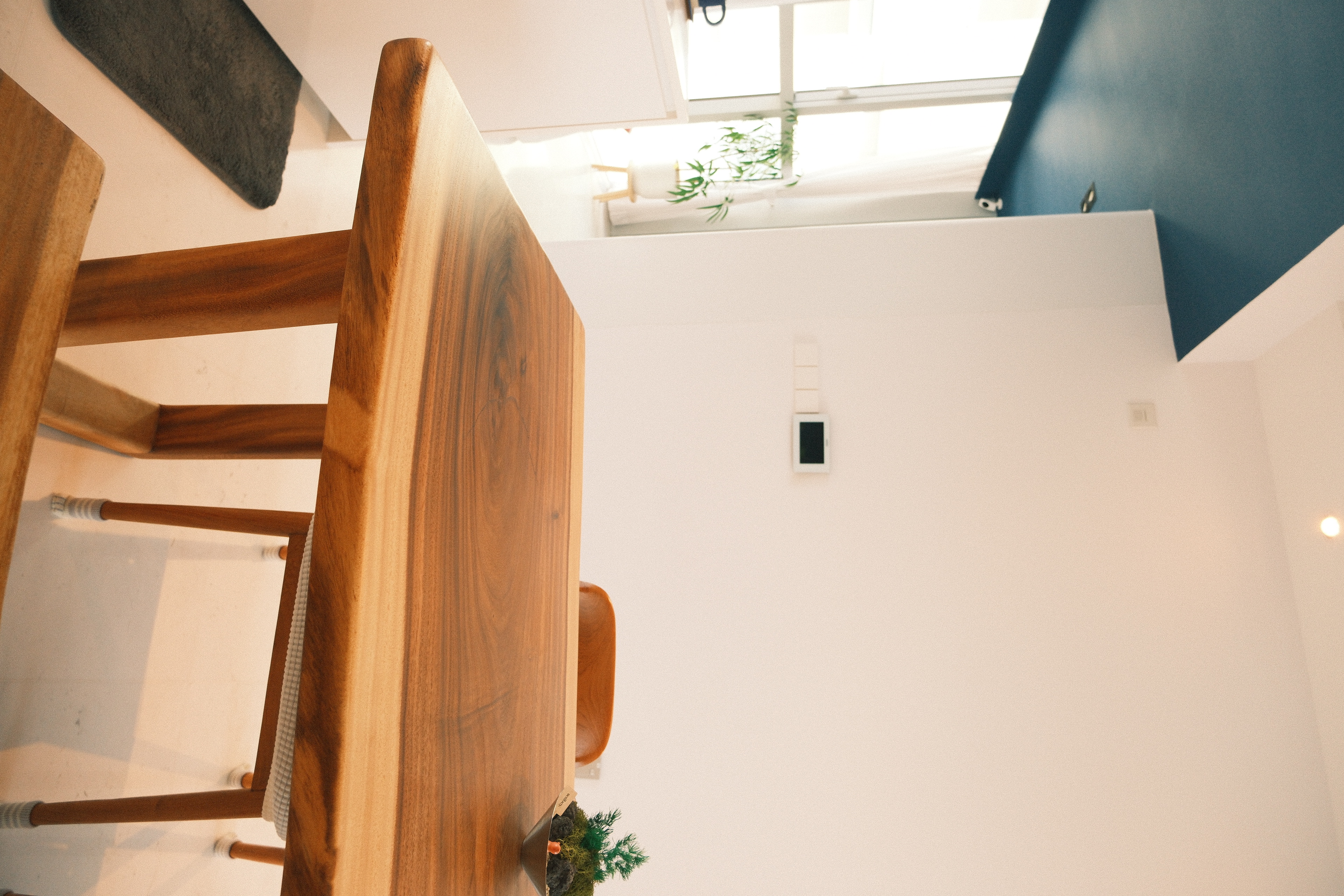 Wes Anderson-style dining room with warm woody tones  - Wooden dining table, minimalist design, modern interior, white walls