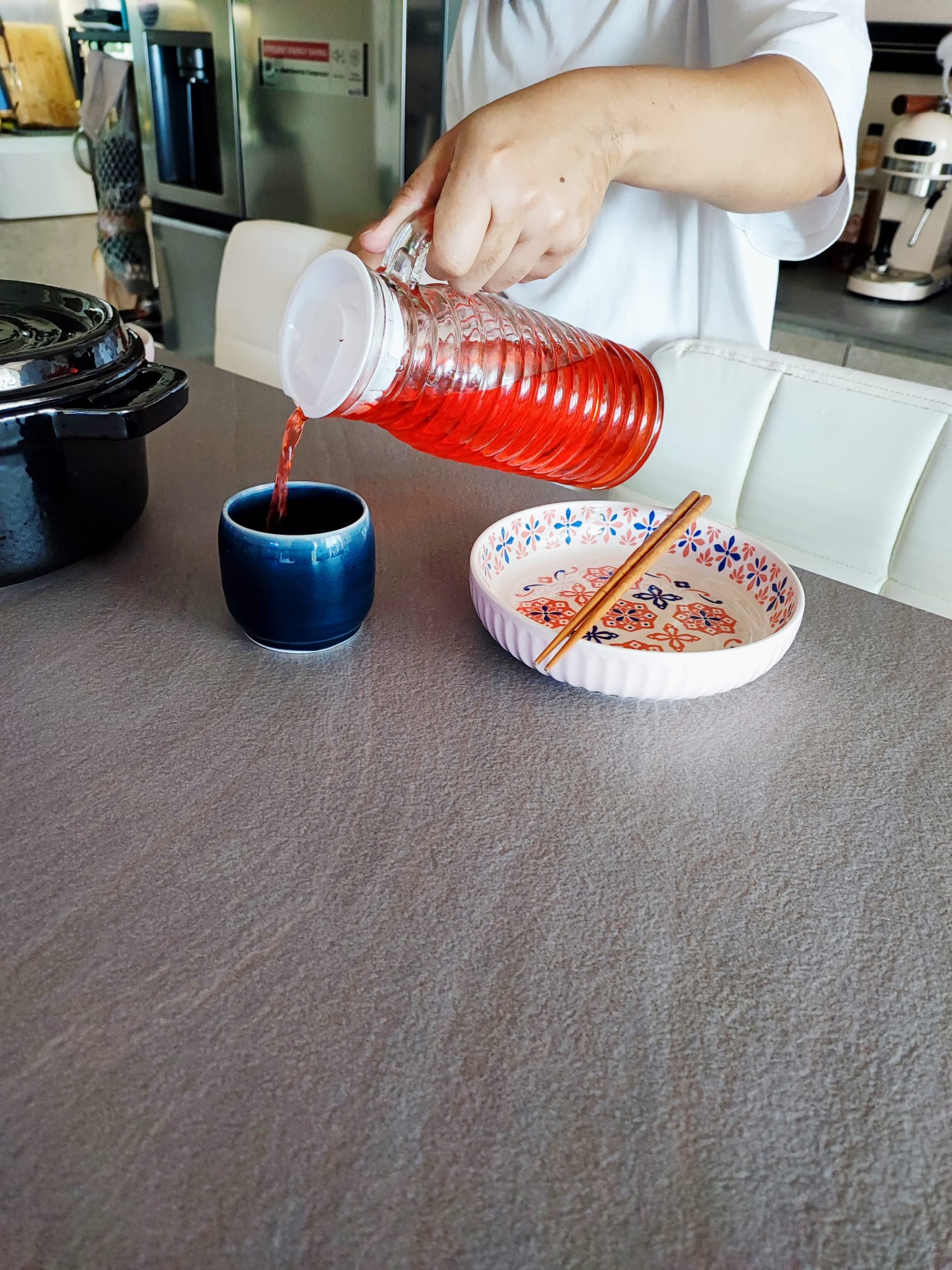 A multifunctional dining area, but on wheels! - vibrant red liquid, pouring from bottle, person pouring, blue cup, ceramic