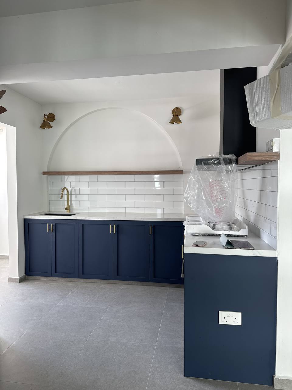 How much do arches cost?  - Modern kitchen with dark blue cabinetry, white subway tiles, gold faucet, arched ceiling