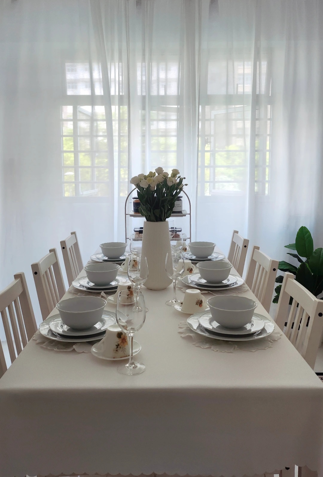 Hosting tips by punggoHField - White dining table, elegant table setting, floral centerpiece, sheer curtains, natural light
