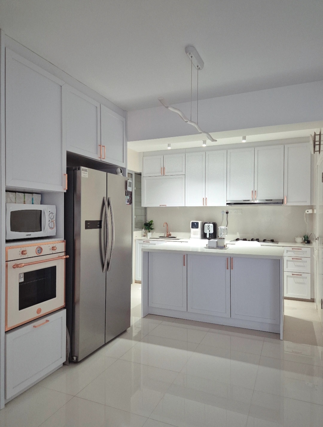 Hosting tips by punggoHField - Modern kitchen with sleek white cabinets and countertops, stainless steel refrigerator