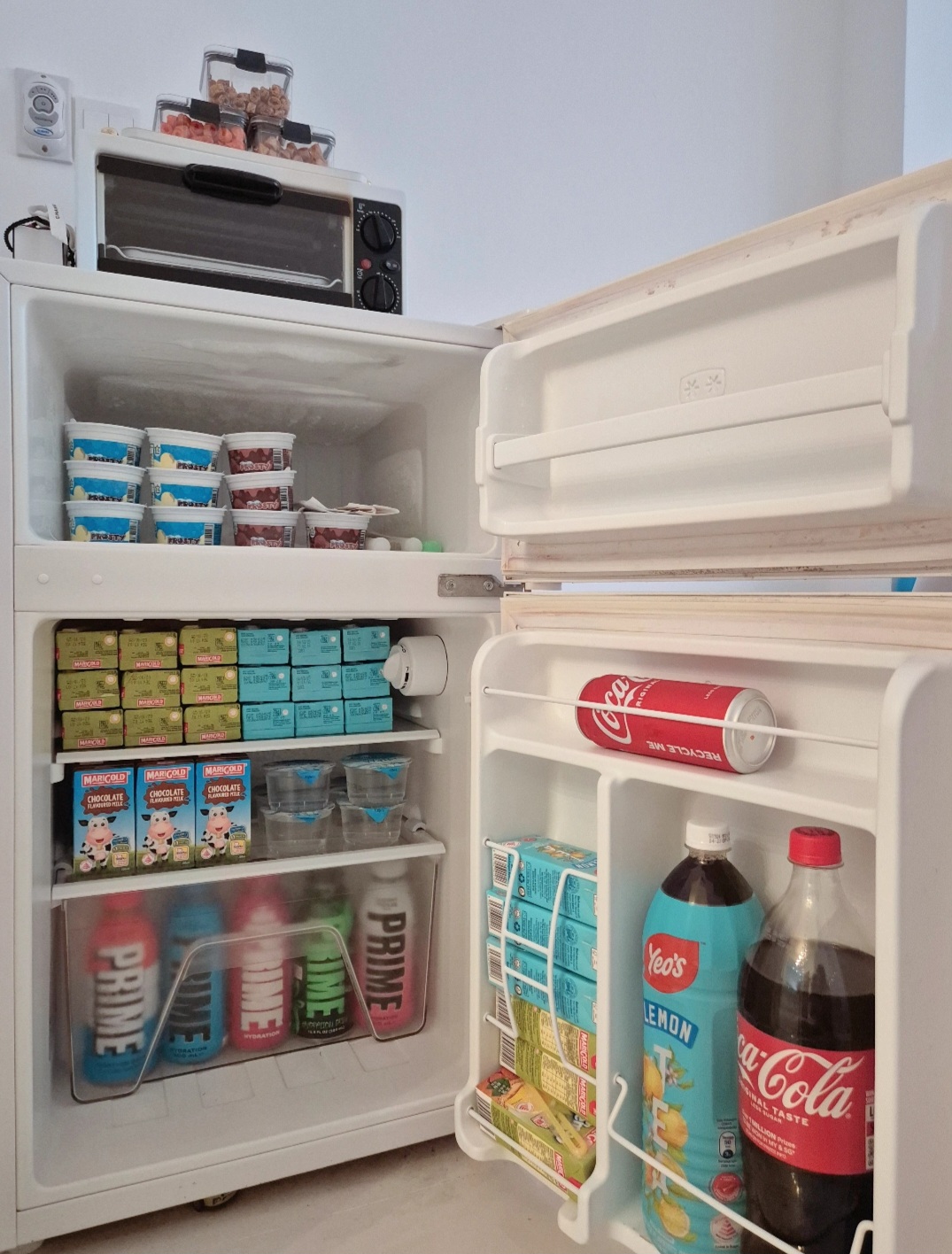 Hosting tips by punggoHField - Mini fridge stocked with various beverages, including milk, yogurt, juice, and soft drinks.