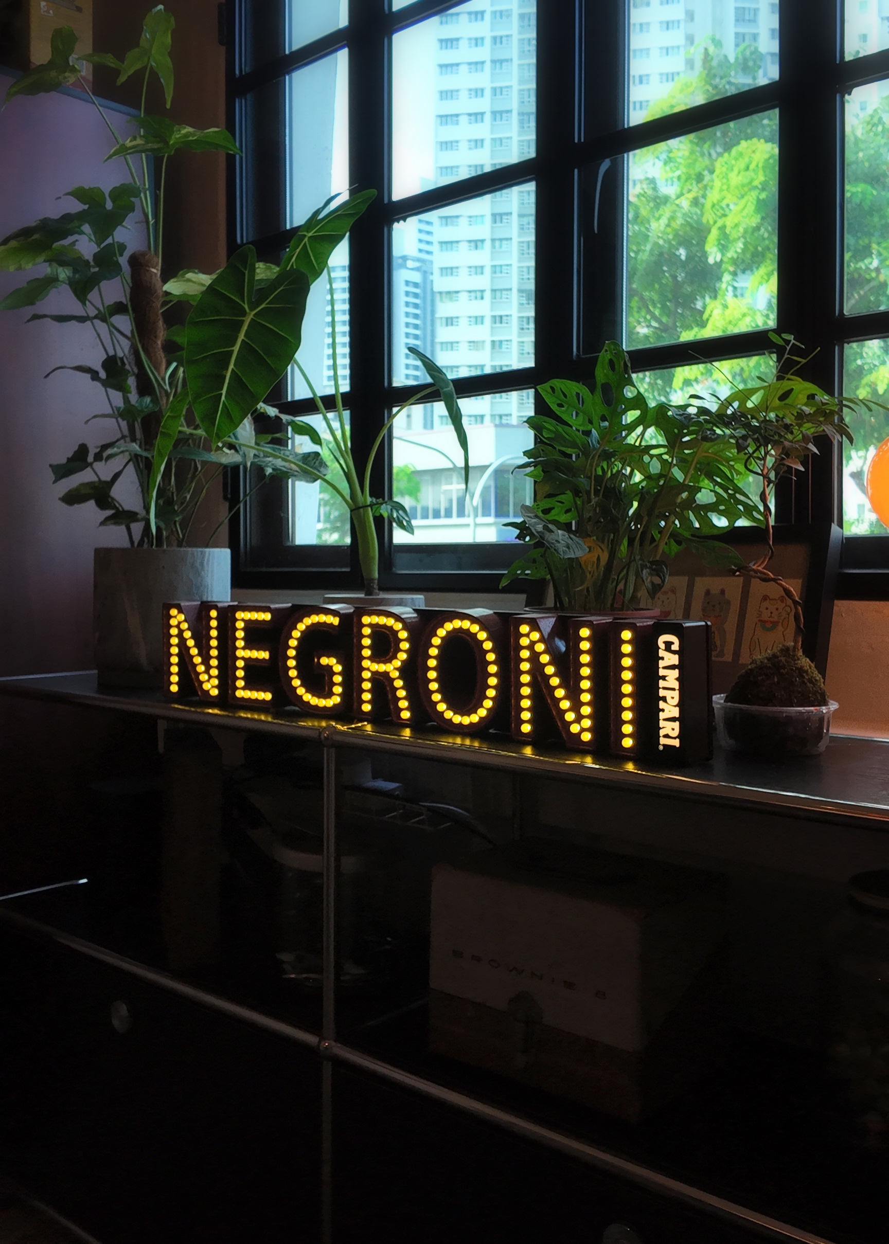 Ling, Ling! Dinner’s served!  - LED sign with "NEGRONI" illuminated in bright yellow lights, placed on a desk next to a