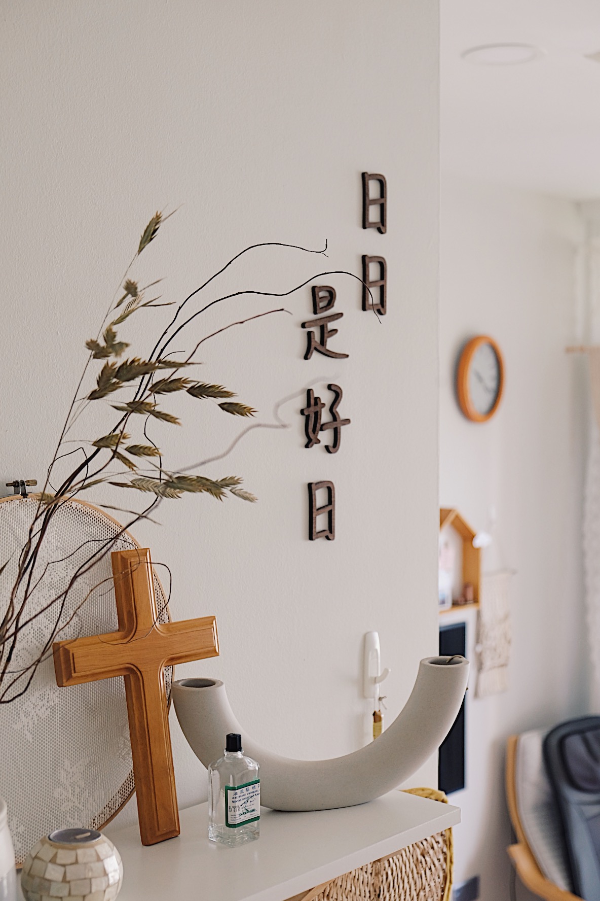 Styling a cosy dining nook in a small home - Wooden cross, white shelf, dried plants, wooden wall art, Chinese characters