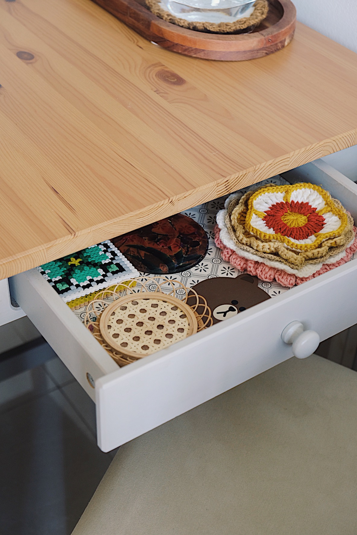 Styling a cosy dining nook in a small home - Wooden table, open drawer, colorful crocheted items, woven basket, decorative