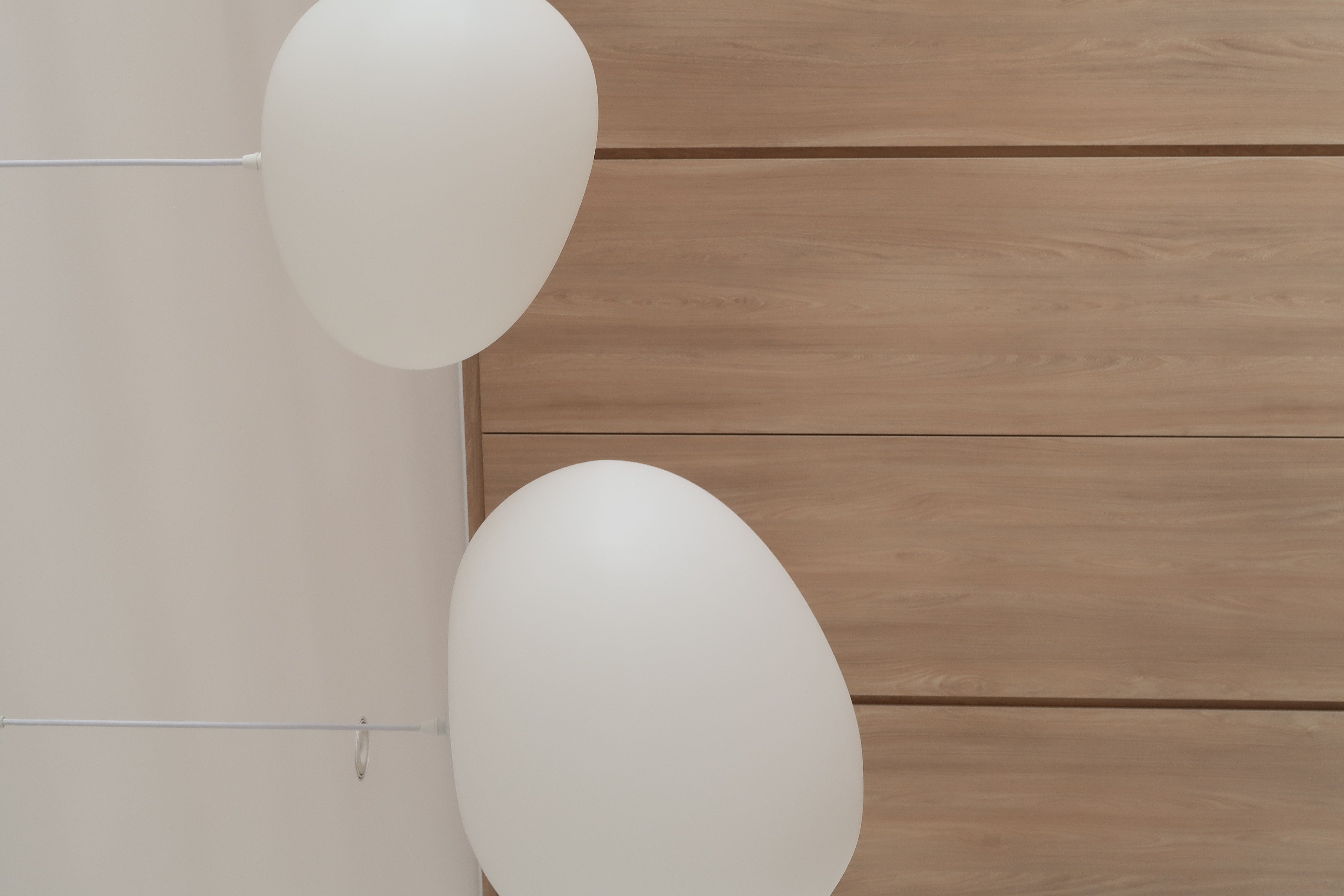 Dining Space: A Cosy Haven for Gatherings and More - White balloons hanging from a ceiling, wooden wall panel background