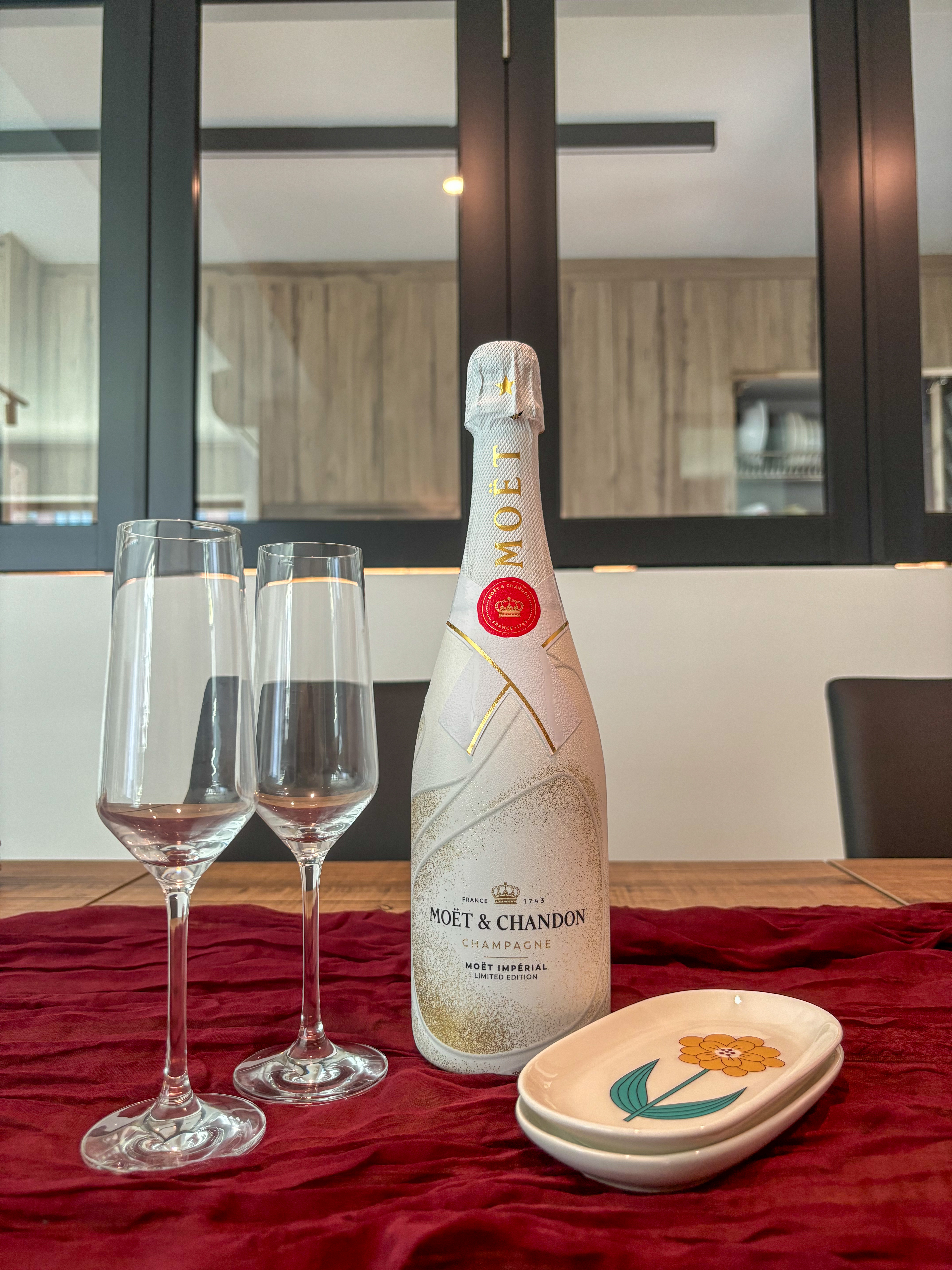 Minimalist Dining Area with Half Wall Partition - Champagne bottle with Moet & Chandon logo, empty champagne glasses, elegant
