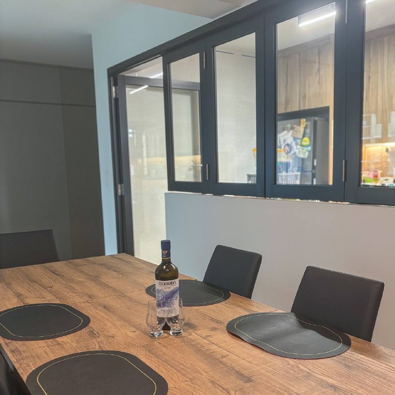 Minimalist Dining Area with Half Wall Partition - Wooden dining table, modern kitchen, black chairs, wine bottle, clear