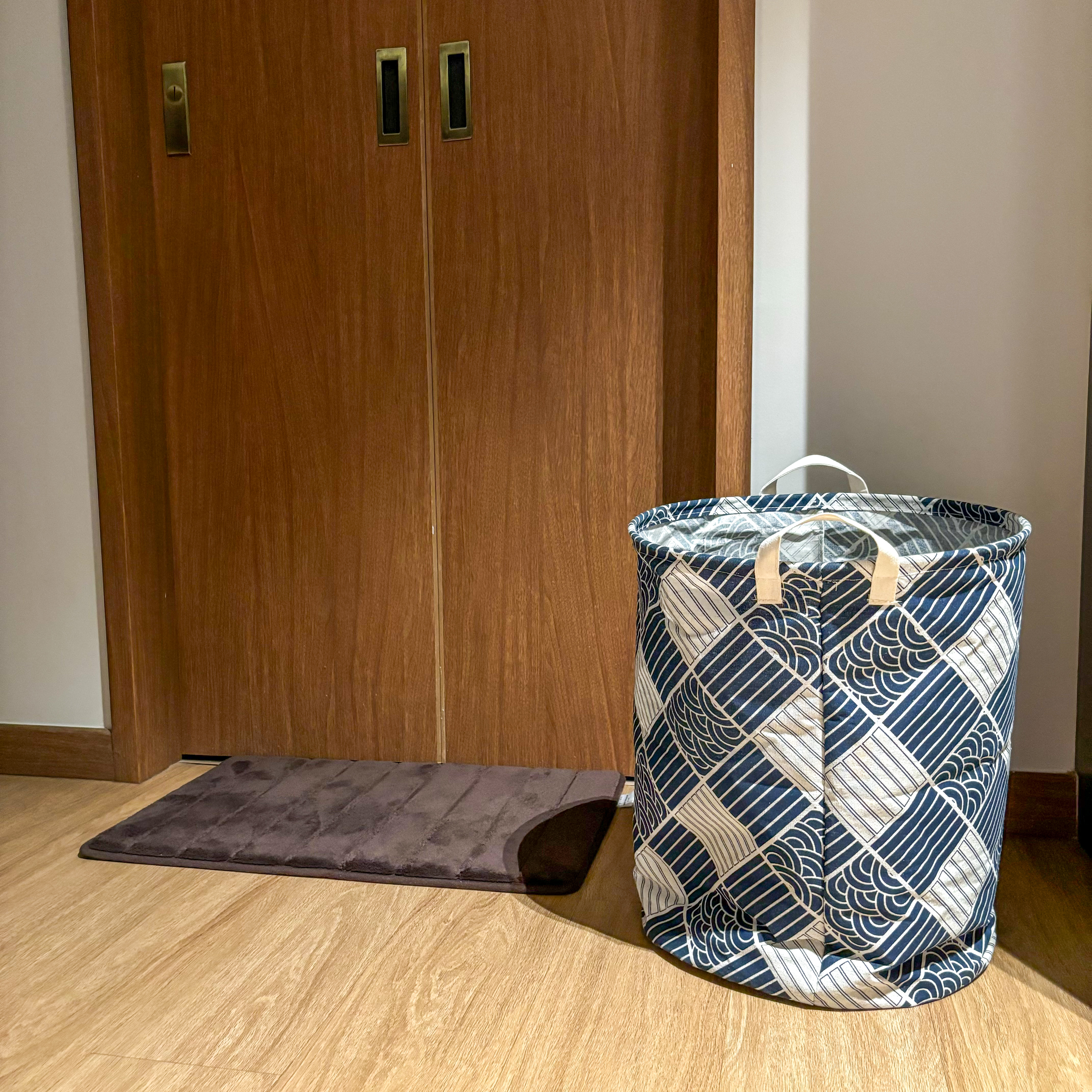 Cozy bedroom with muted tones  - Wooden door with brass handles, blue and white patterned laundry basket, brown wooden floor