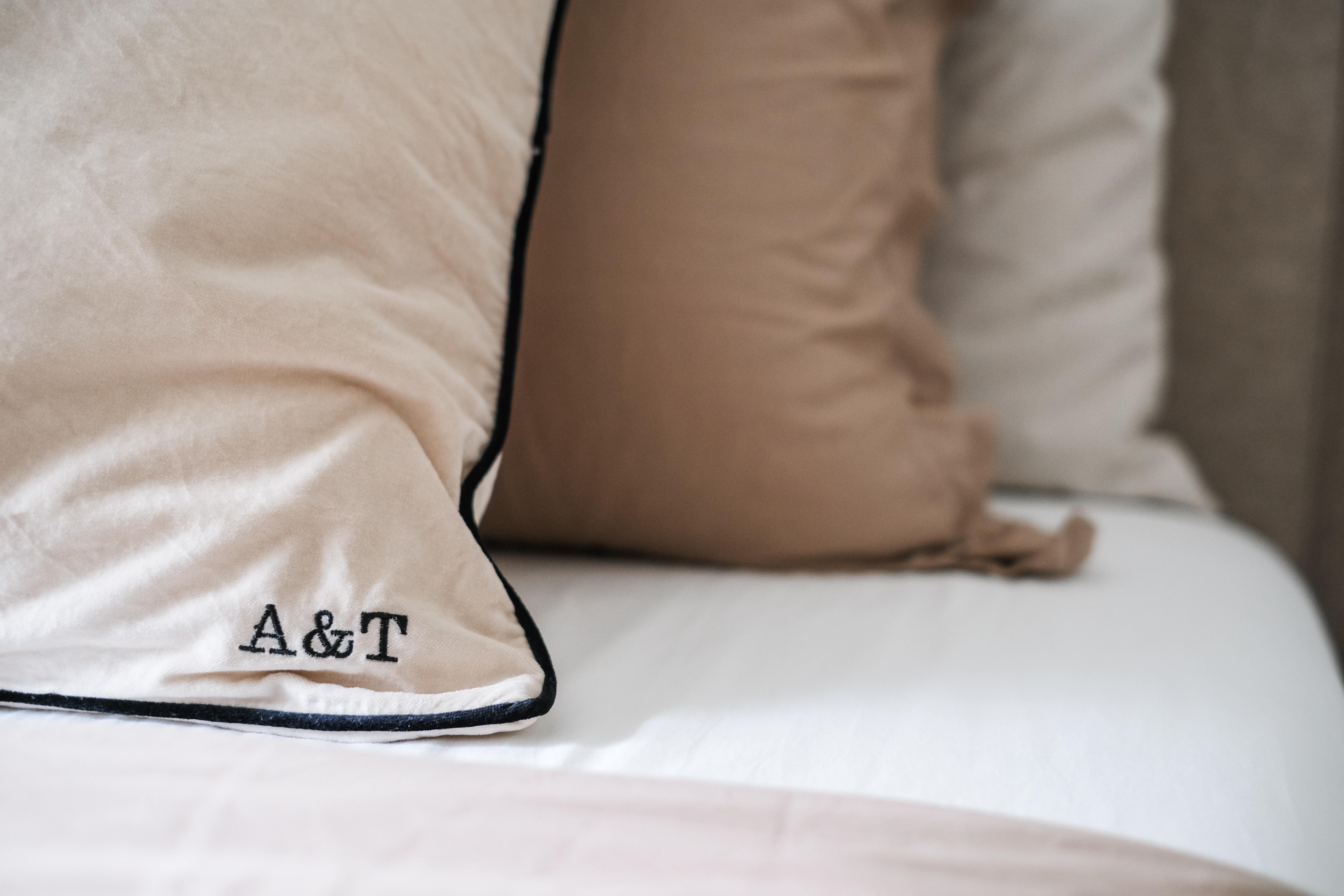 Calming Modern Bedroom in Creme Tones with DIY Wall Art - Soft beige and brown pillows, embroidered initials A&T, plush