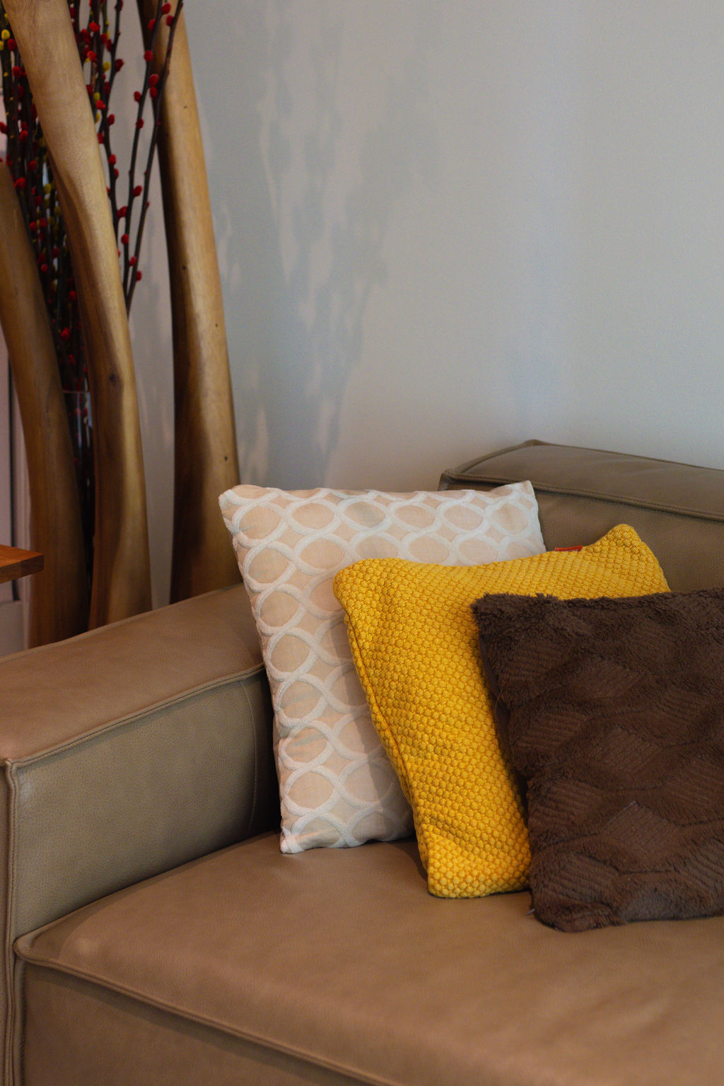 Home-Styling Tips: Achieving a cohesive island-living inspired home  - Wooden sculpture, beige couch, yellow textured pillow