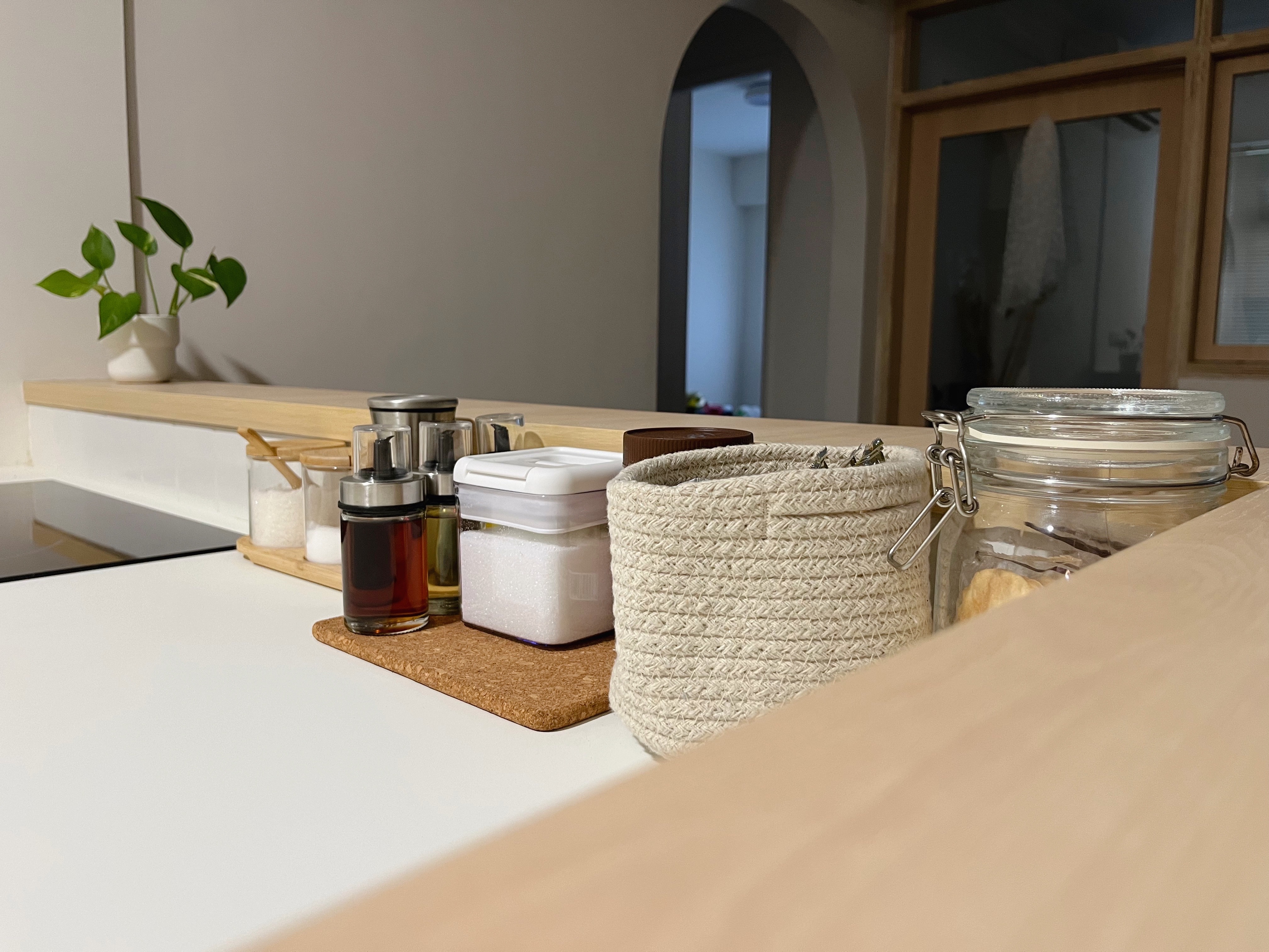 Organising our kitchen counter with items under $5 - glass jars, wooden shelf, potted plant, white countertop, beige woven
