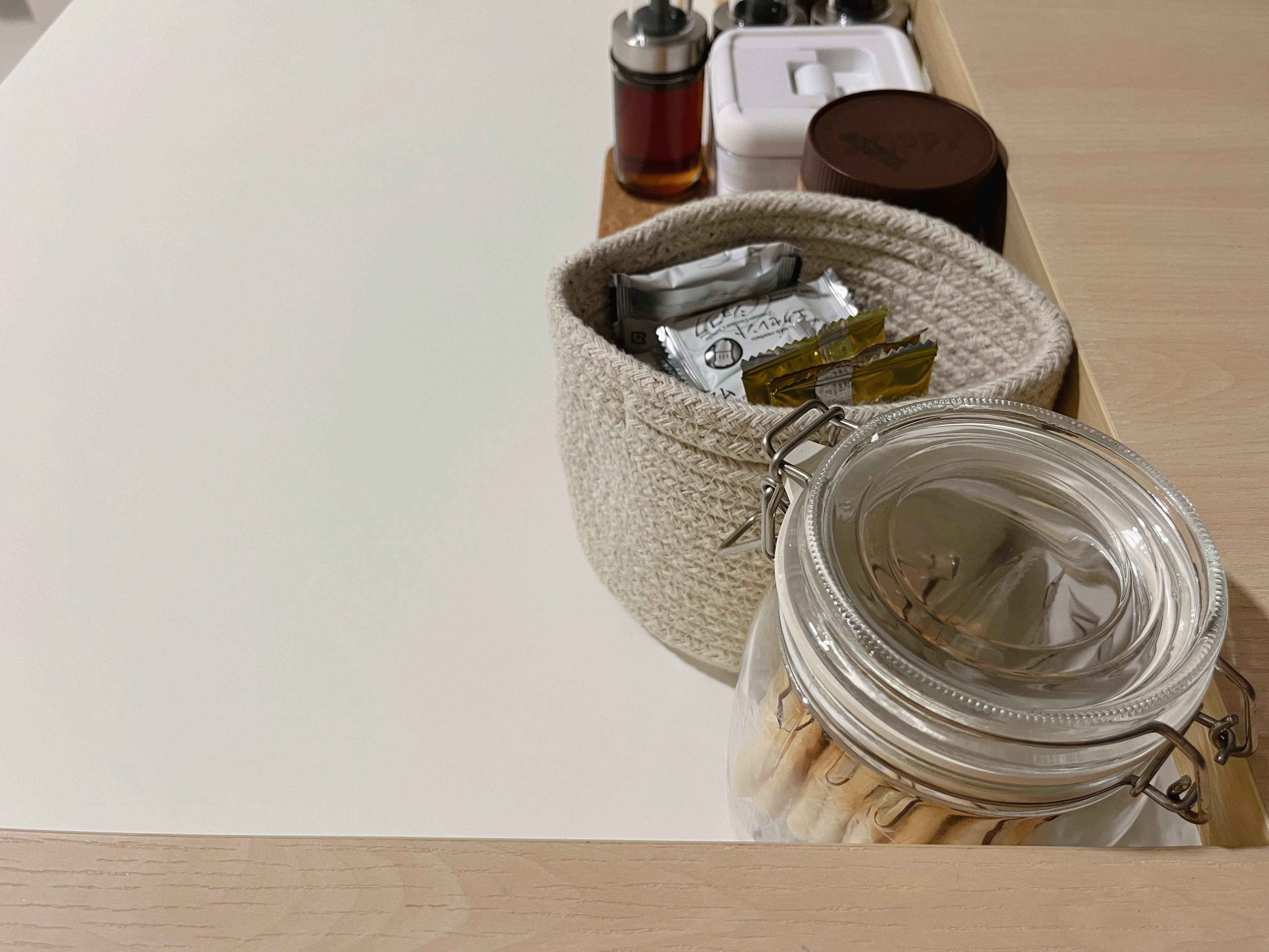 Organising our kitchen counter with items under $5 - glass jar, neatly arranged, wooden surface, beige basket, silver lid