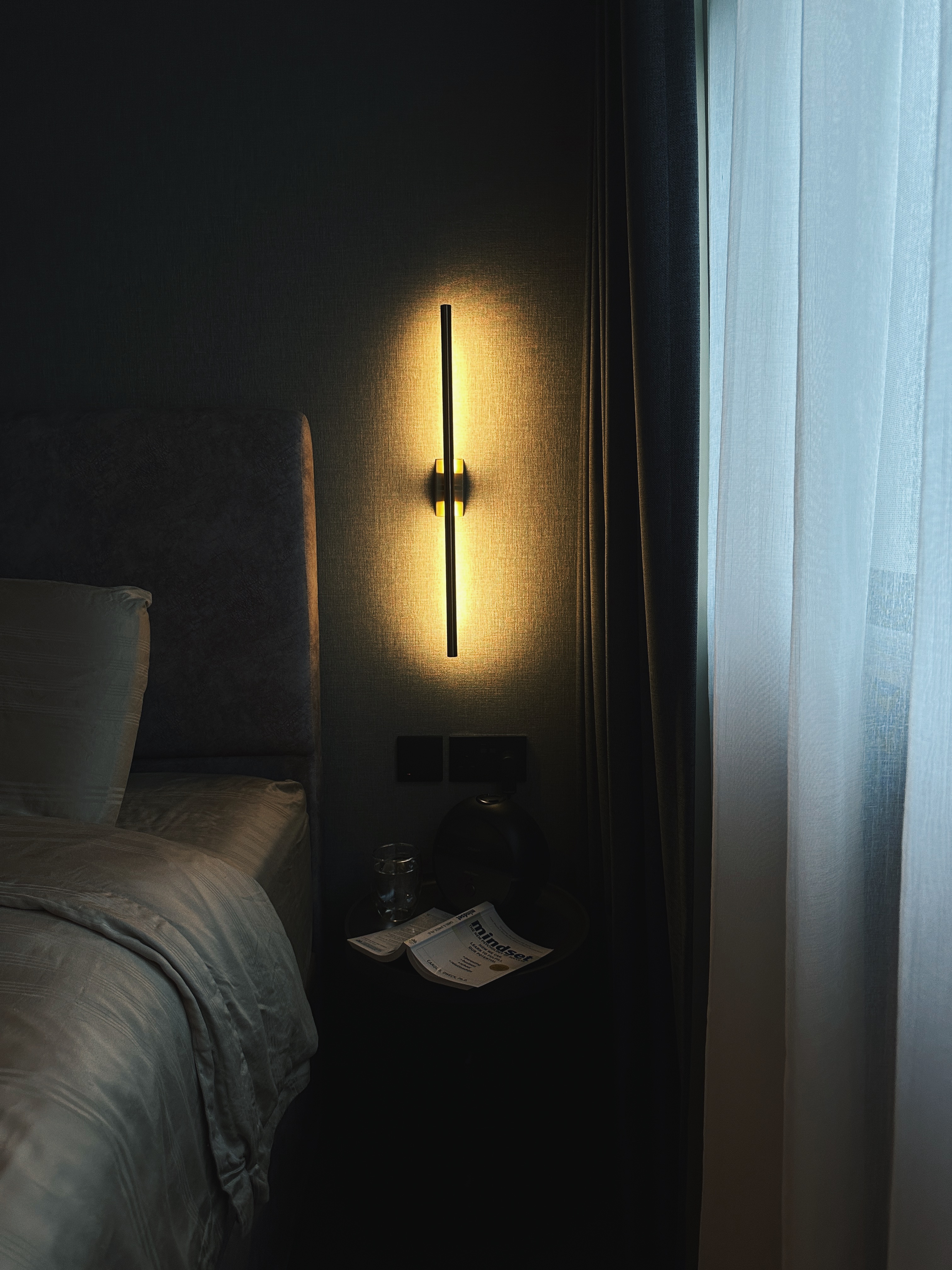 Finding Comfort: A Glimpse into Our Cozy and Minimalist Bedroom - dimly lit bedroom, modern decor, bedside table, soft