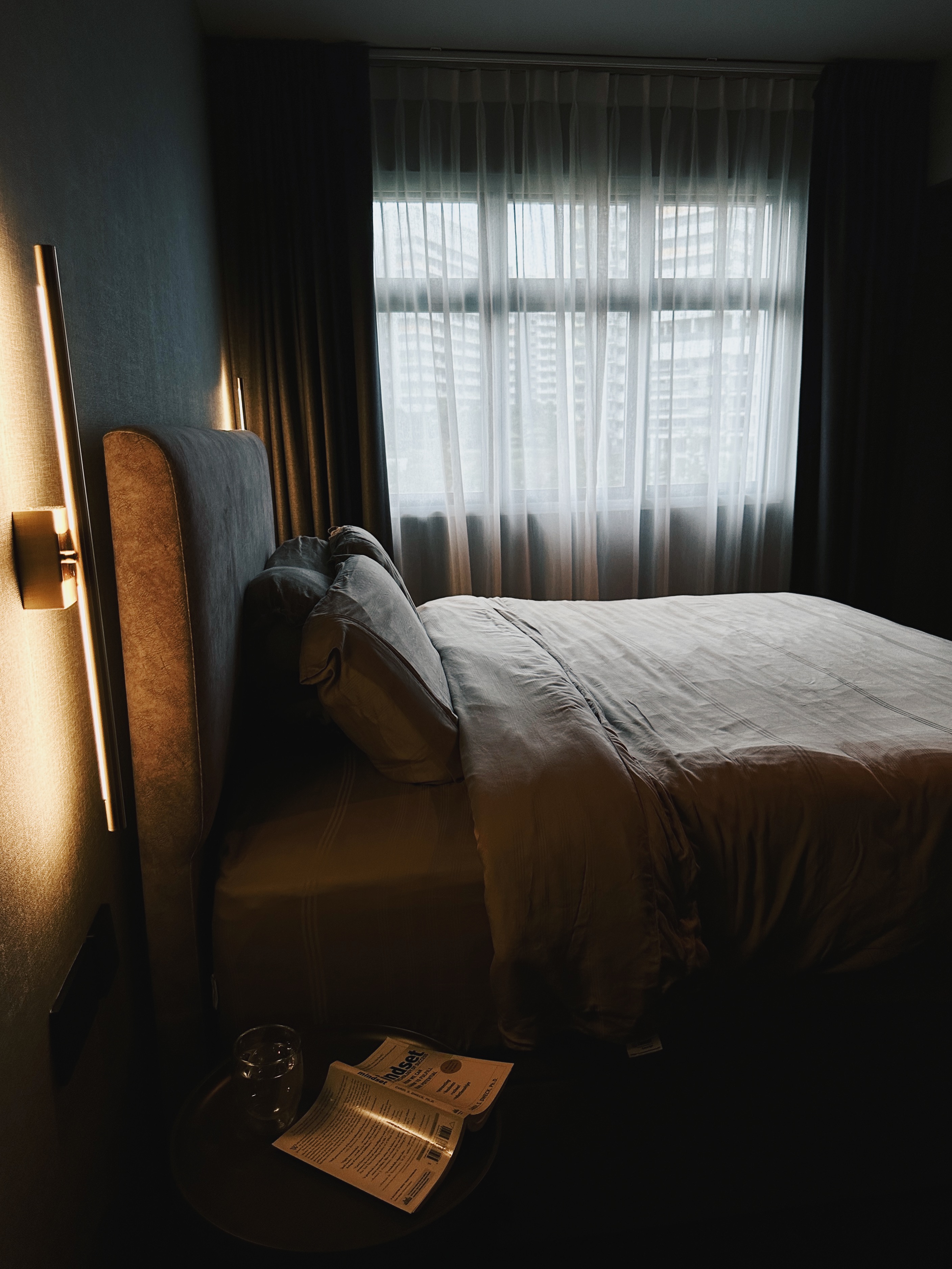 Finding Comfort: A Glimpse into Our Cozy and Minimalist Bedroom - dimly lit bedroom, cozy atmosphere, soft lighting, bedside
