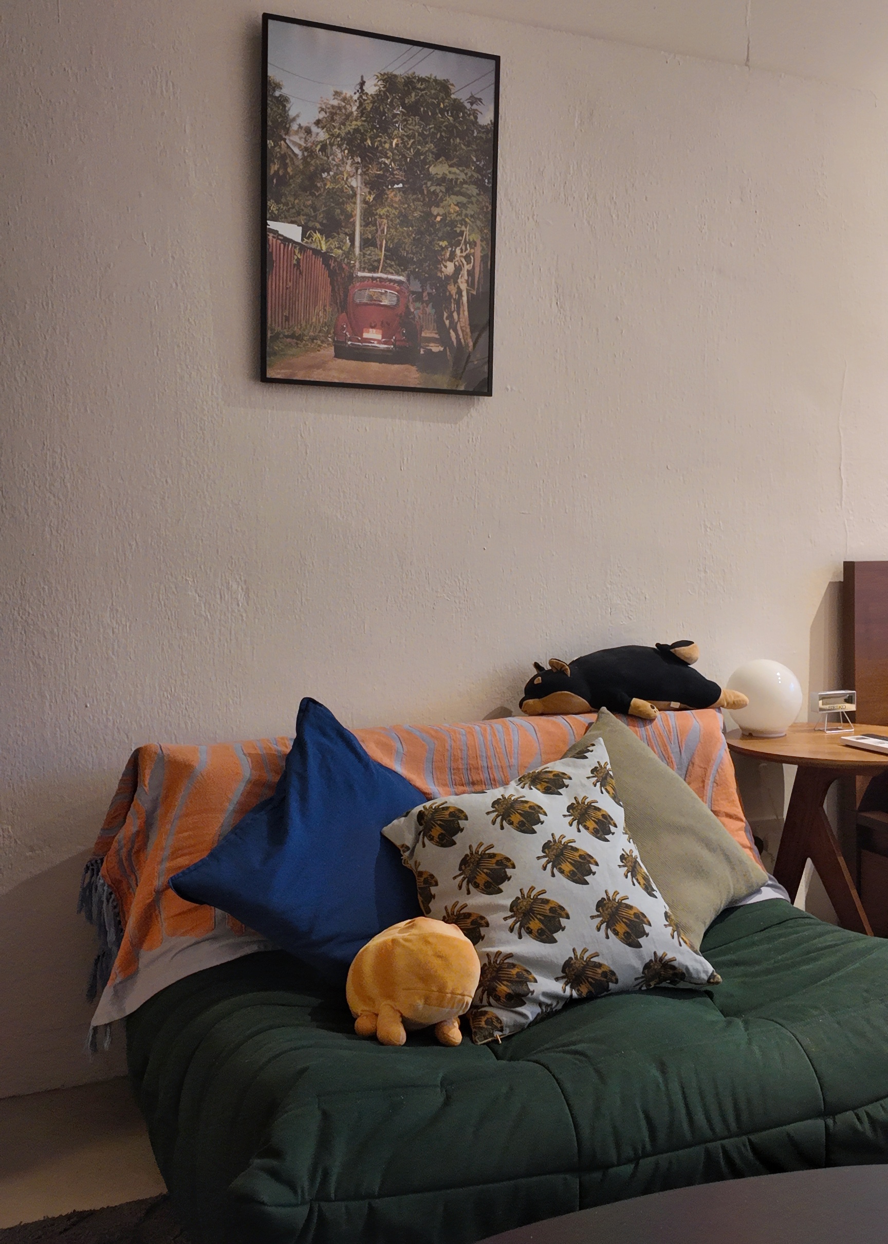 A living room within our bedroom - vintage red car, cozy sofa, orange and blue pillows, plush toy, black stuffed animal