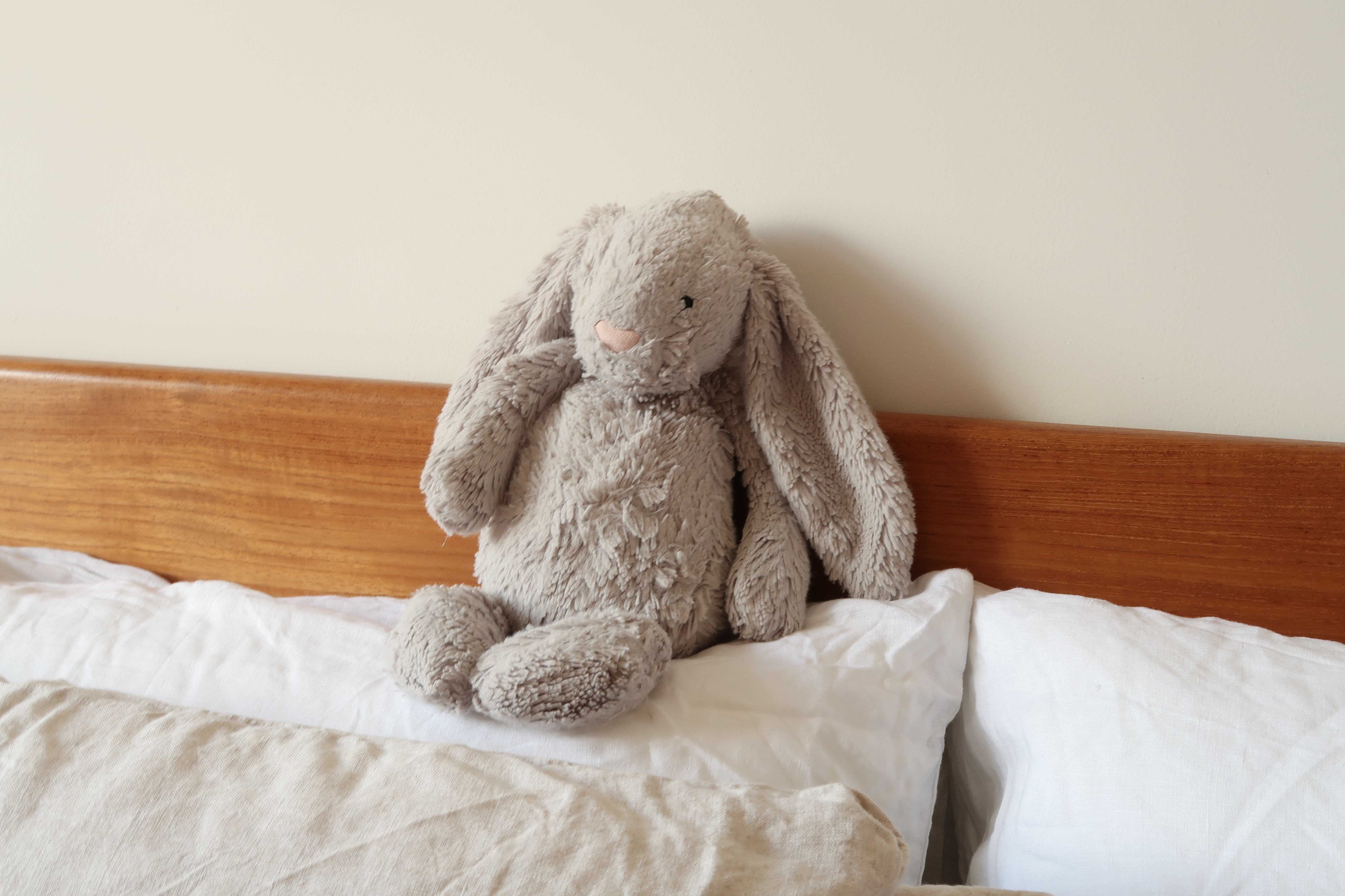 Master Bedroom: A Peaceful Retreat - Soft, plush, beige stuffed bunny sits on bed, fluffy ears, white pillows, wooden