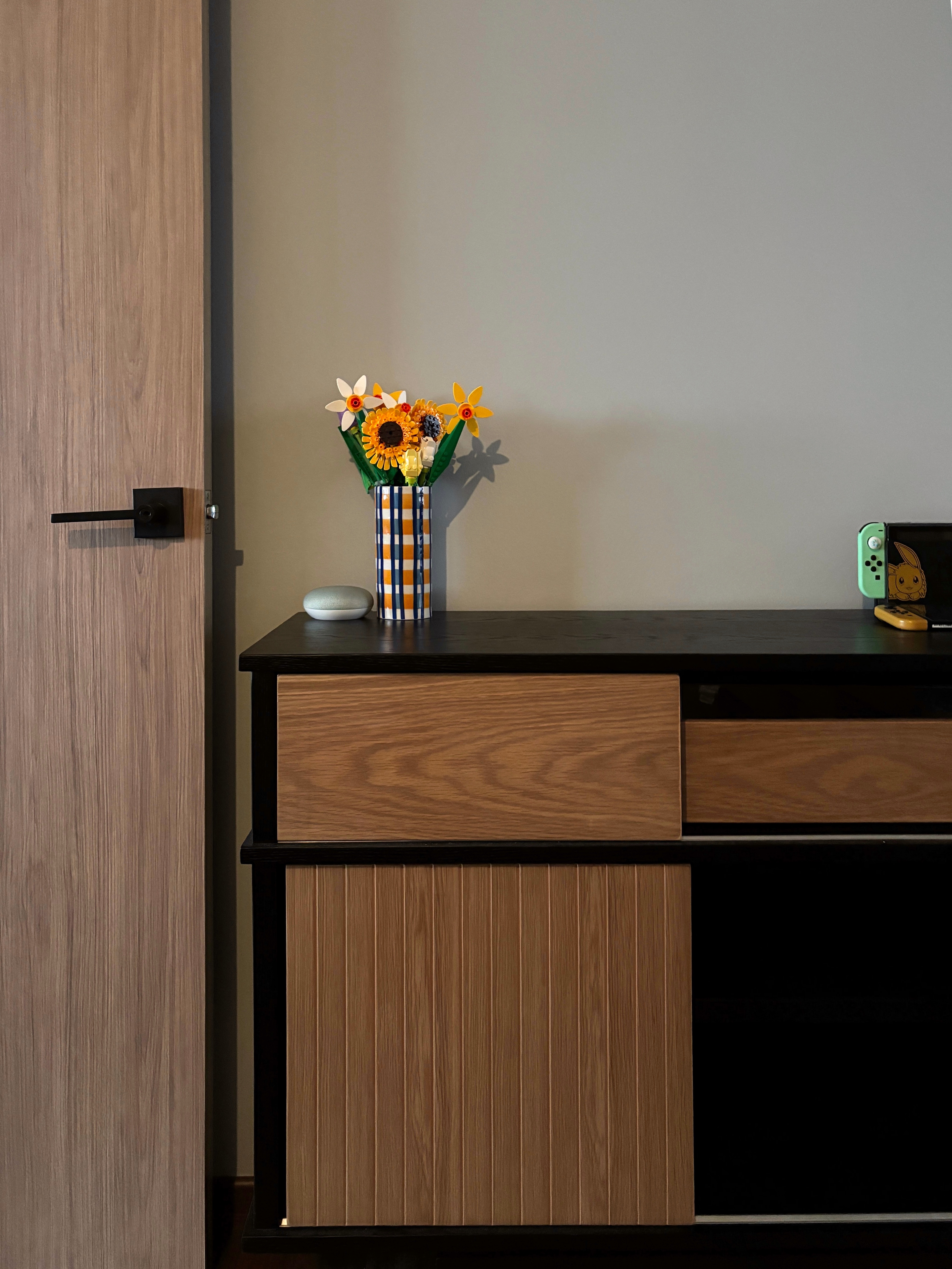 Transforming Our Bedroom from Minimal to Cosy  - Wooden door, black handle, vase with flowers, yellow sunflowers, green