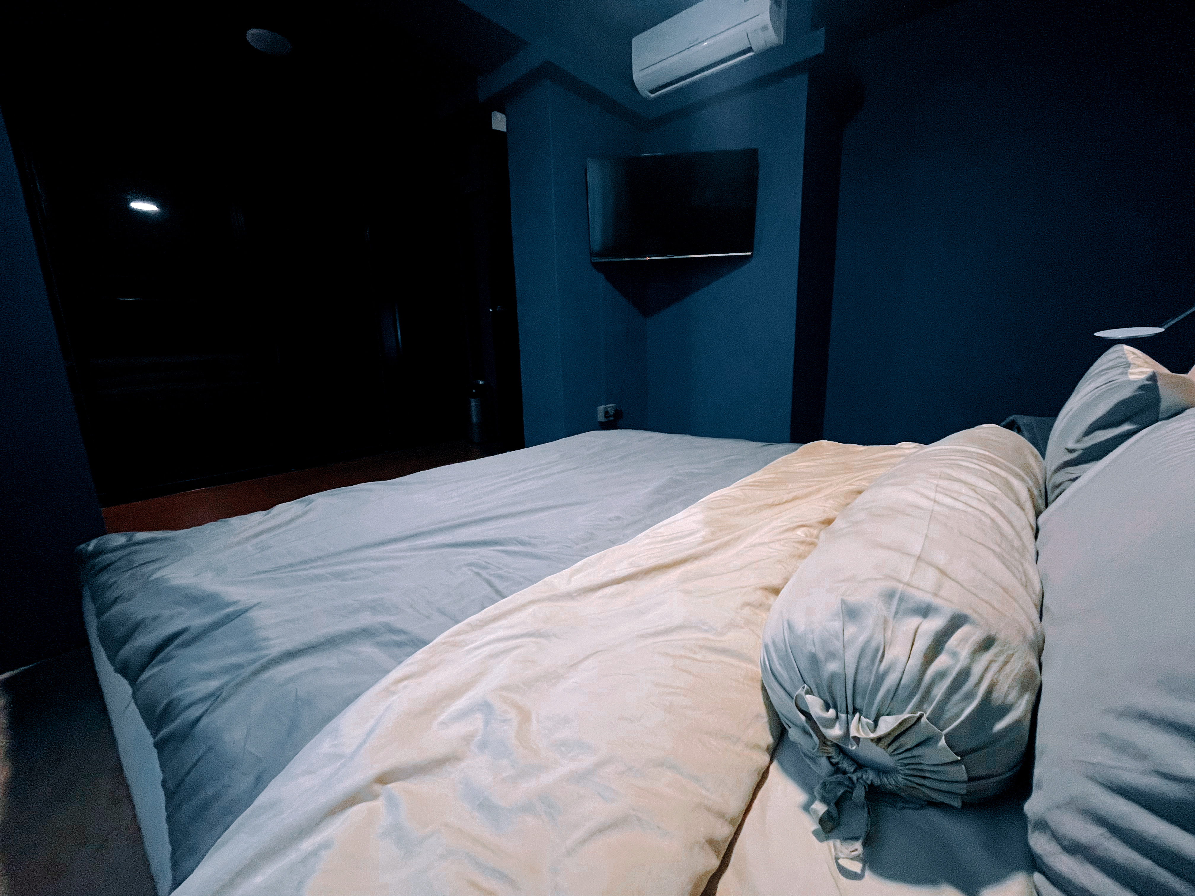 The Perfect Mistake: How a Wrong-Sized Bedframe Completed Our Space - Dark room, dim lighting, blue walls, TV mounted on