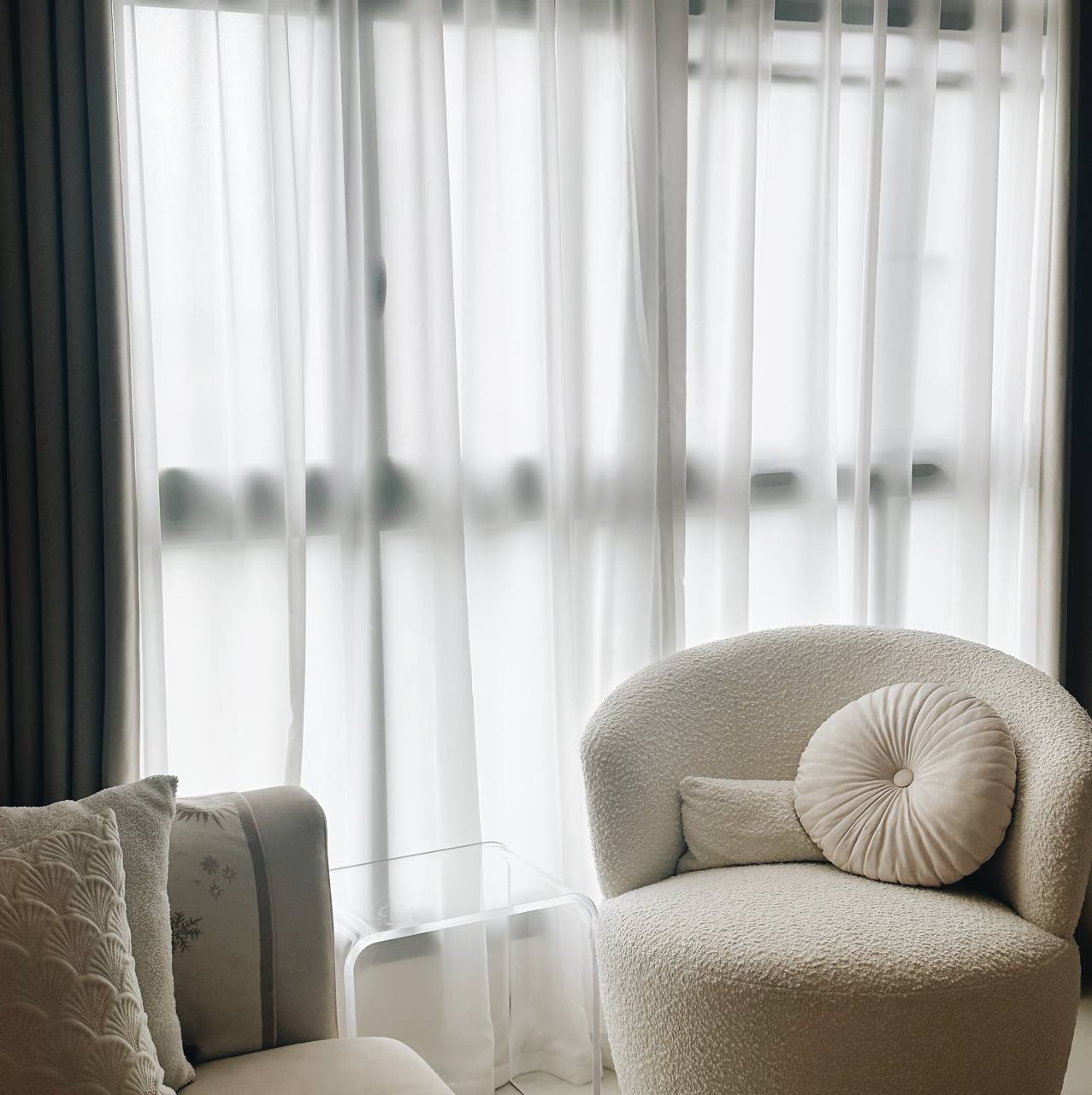 Our Living Room - Modern Minimalist's Dream - Soft, cream-colored sofa with plush cushions, sheer white curtains framing a